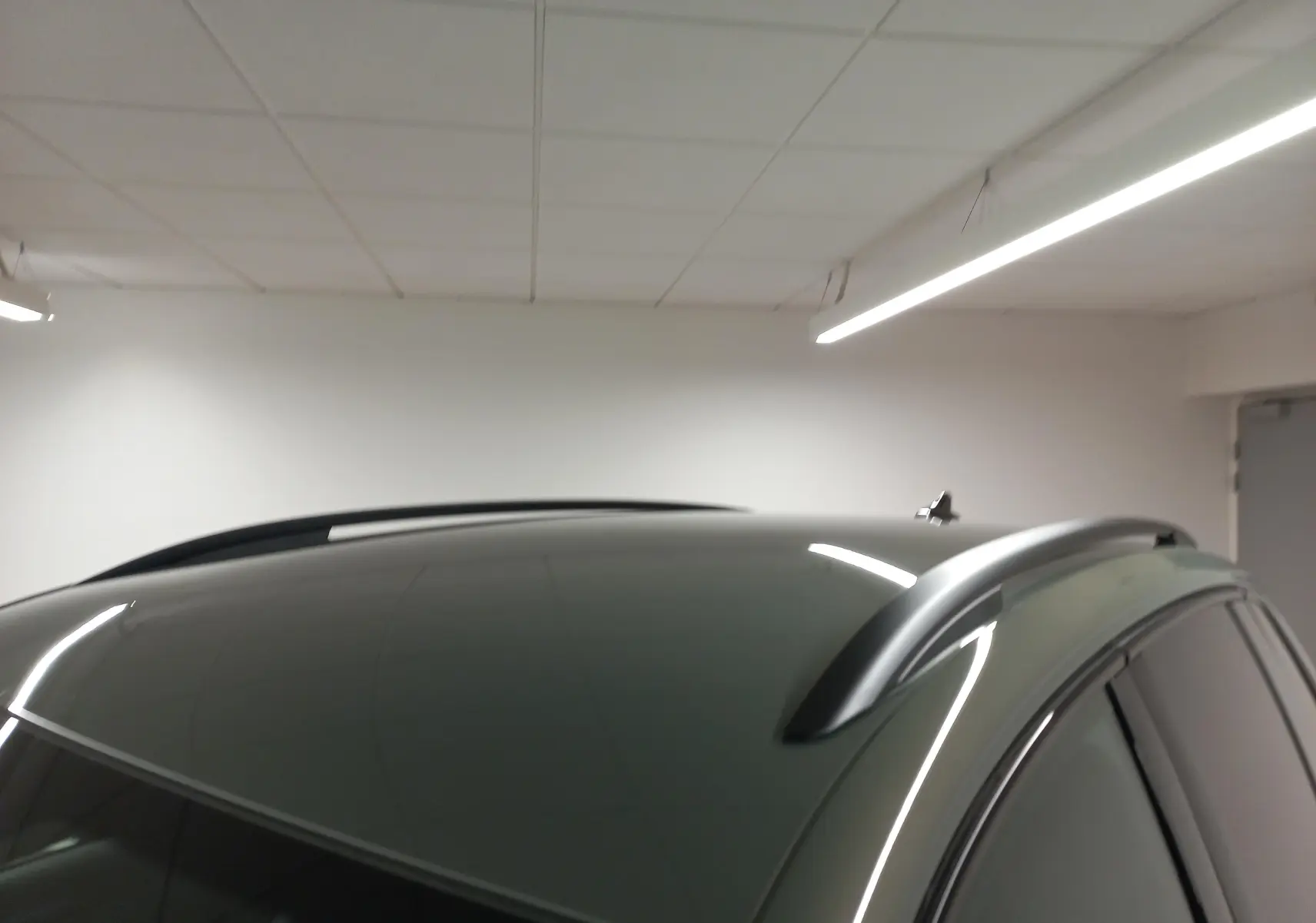 Toit et barres de pavillon noires du Volkswagen Tiguan 2025 en Vert Cipressino, vue partielle côté droit en intérieur.