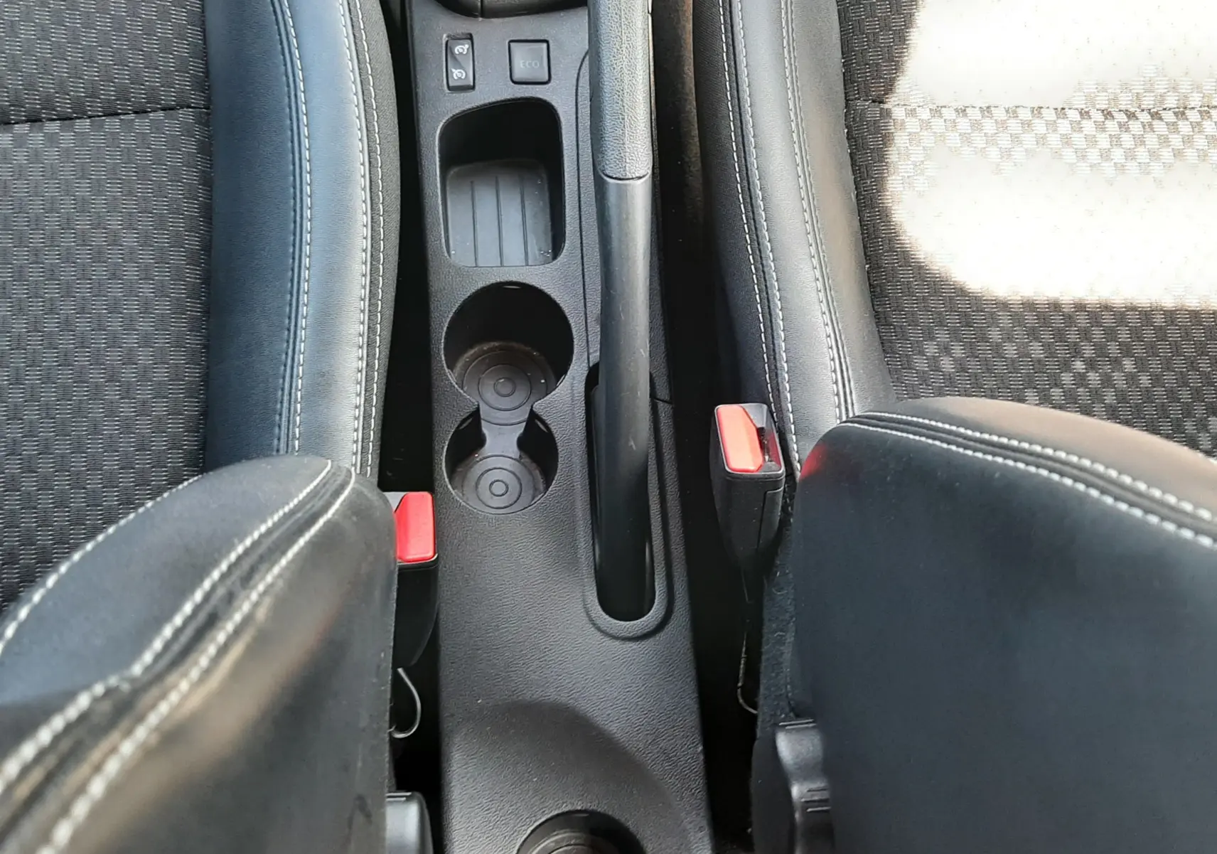 Vue plongeante sur la console centrale noire entre les sièges avant en tissu et cuir de la Renault Clio IV gris titanium.