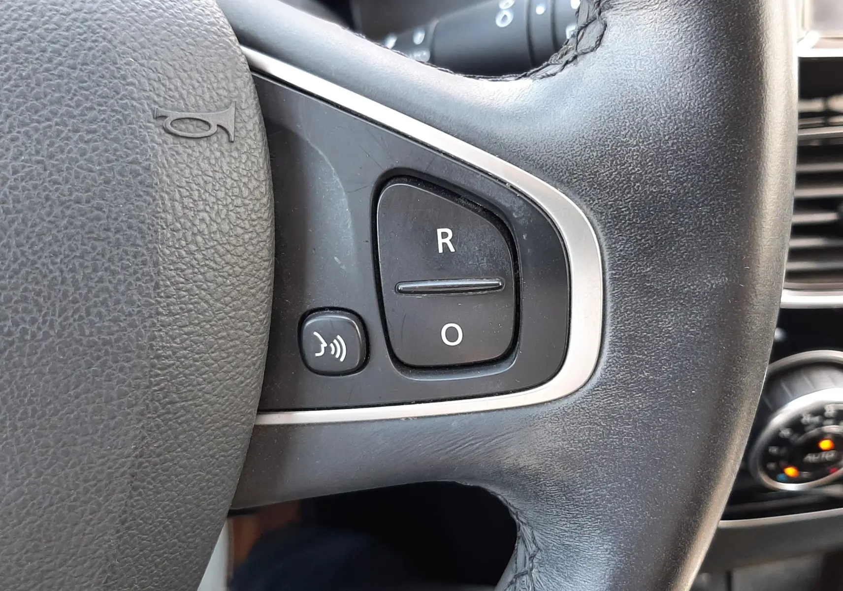 Gros plan sur le volant en cuir noir de la Renault Clio IV 0.9 TCE 90 Intens, avec boutons de commande intégrés.