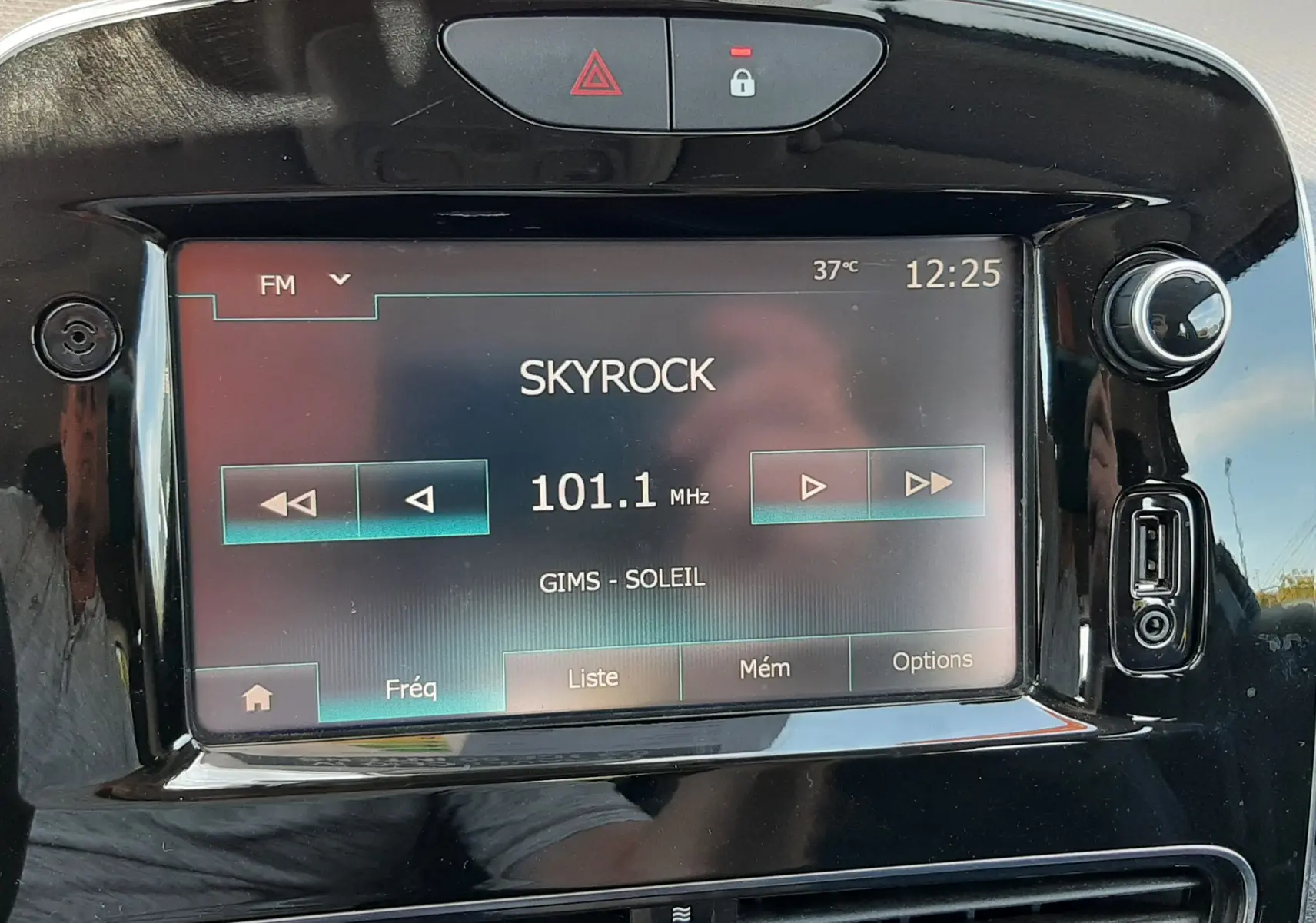 Gros plan sur l’écran tactile central noir de la Renault Clio IV gris titanium, affichant la radio sur 101.1 MHz Skyrock.