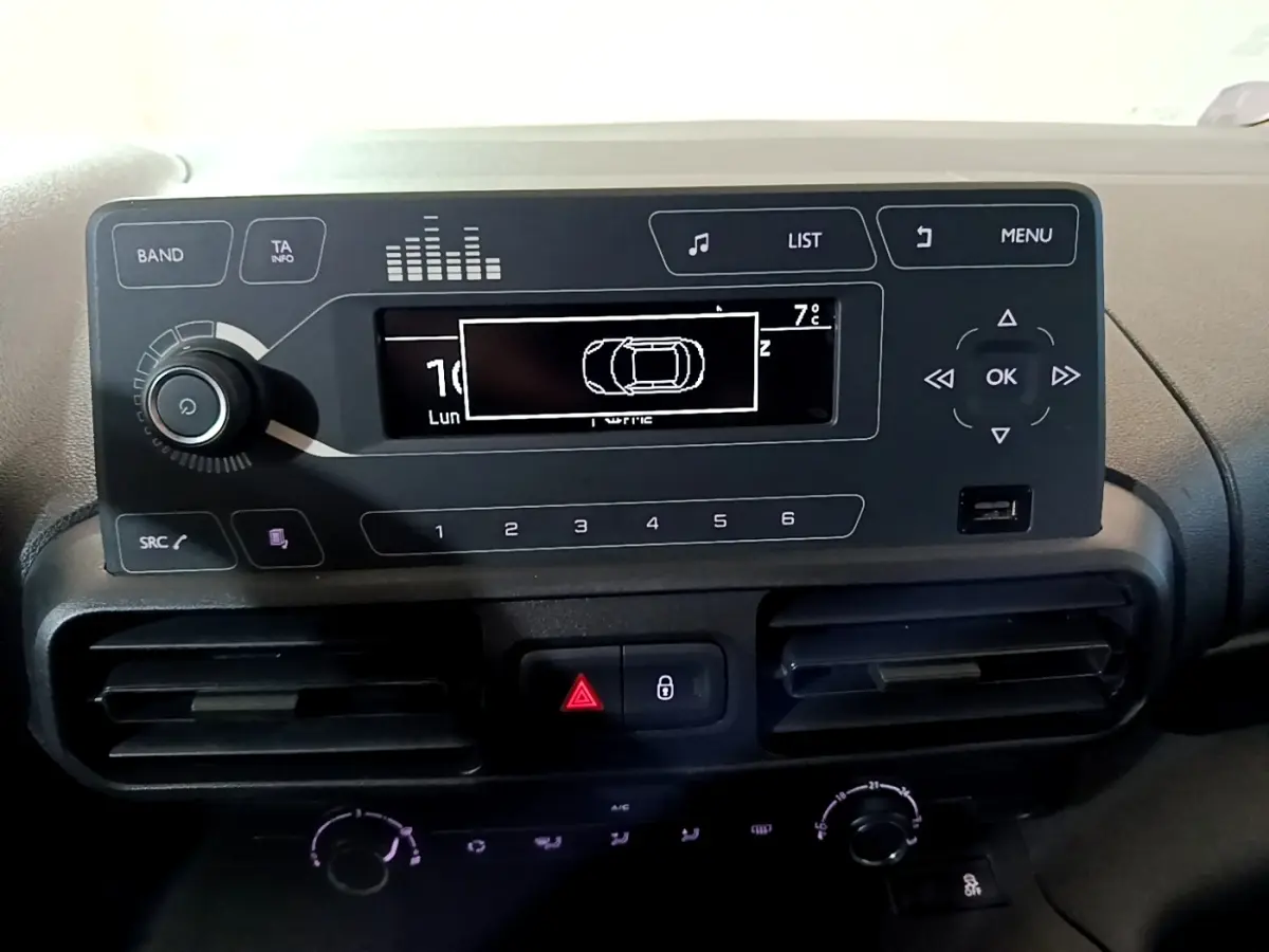 Vue rapprochée du tableau de bord noir du Citroën Berlingo XL blanc, affichage central avec commandes radio et climatisation.