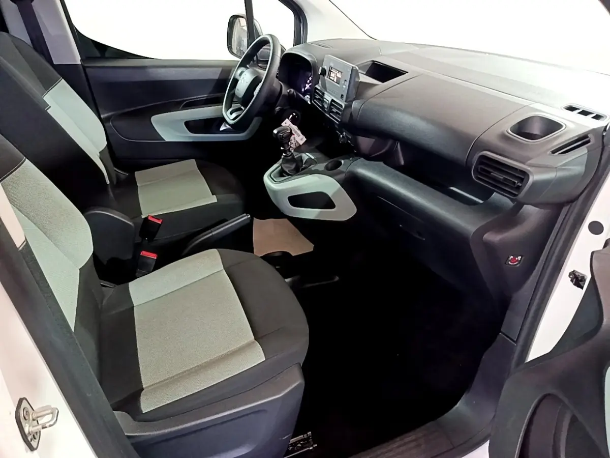 Vue intérieure côté conducteur du Citroën Berlingo XL blanc, montrant sièges tissu bicolore et tableau de bord moderne.