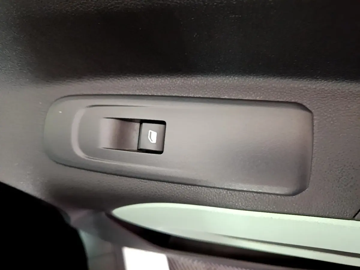 Gros plan sur l'interrupteur de lève-vitre électrique noir dans l'habitacle d'une Citroën Berlingo XL blanc.