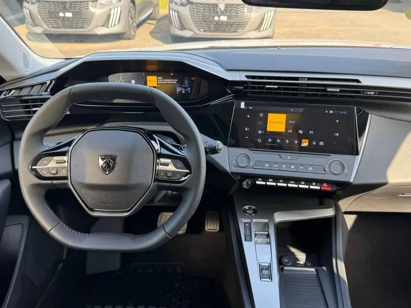 Vue intérieure du poste de conduite de la Peugeot 308 2025, volant compact et écran tactile central moderne.