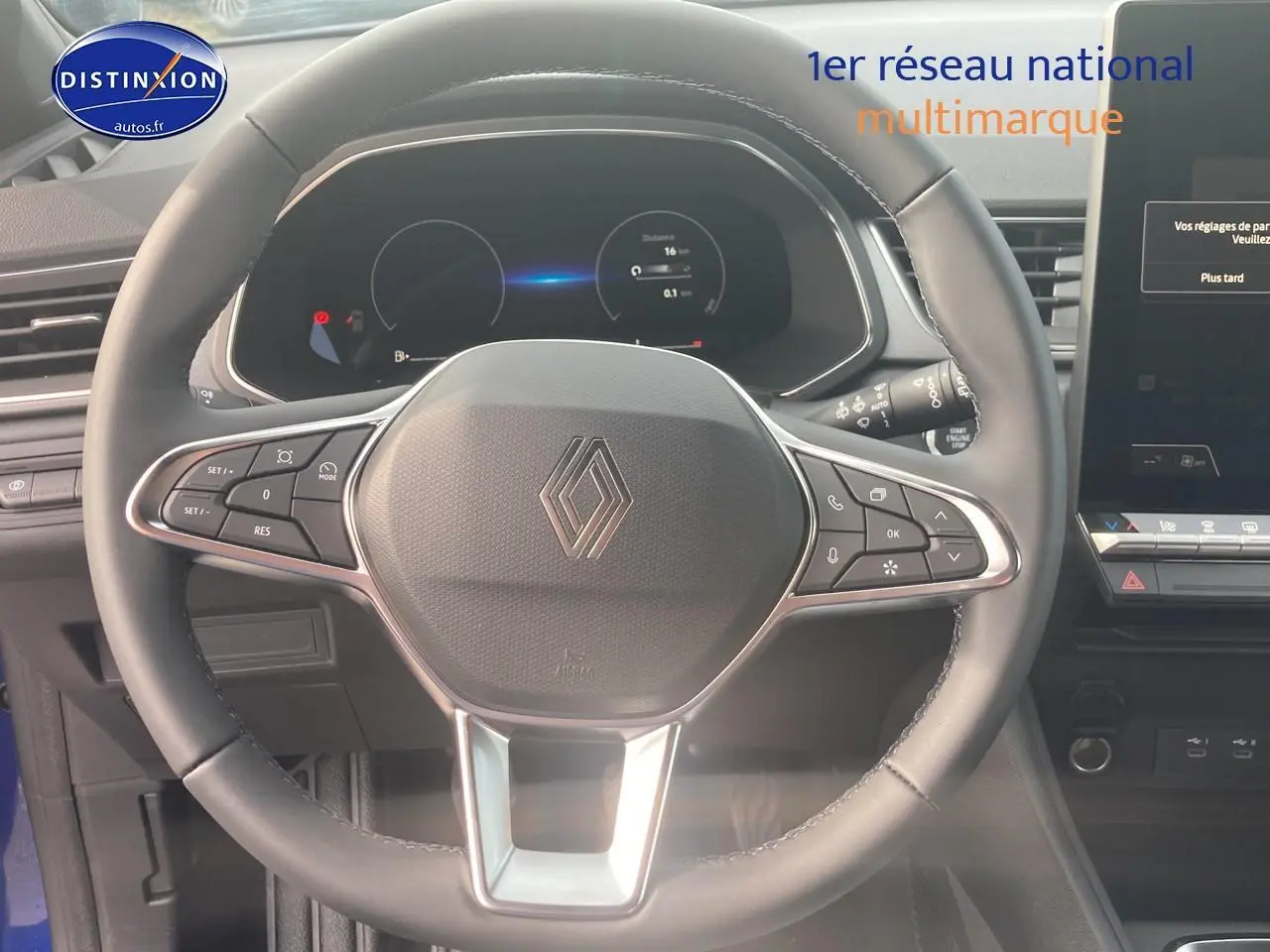 Vue rapprochée du volant multifonction noir du Renault Captur bleu iron, avec tableau de bord numérique et écran tactile visible.