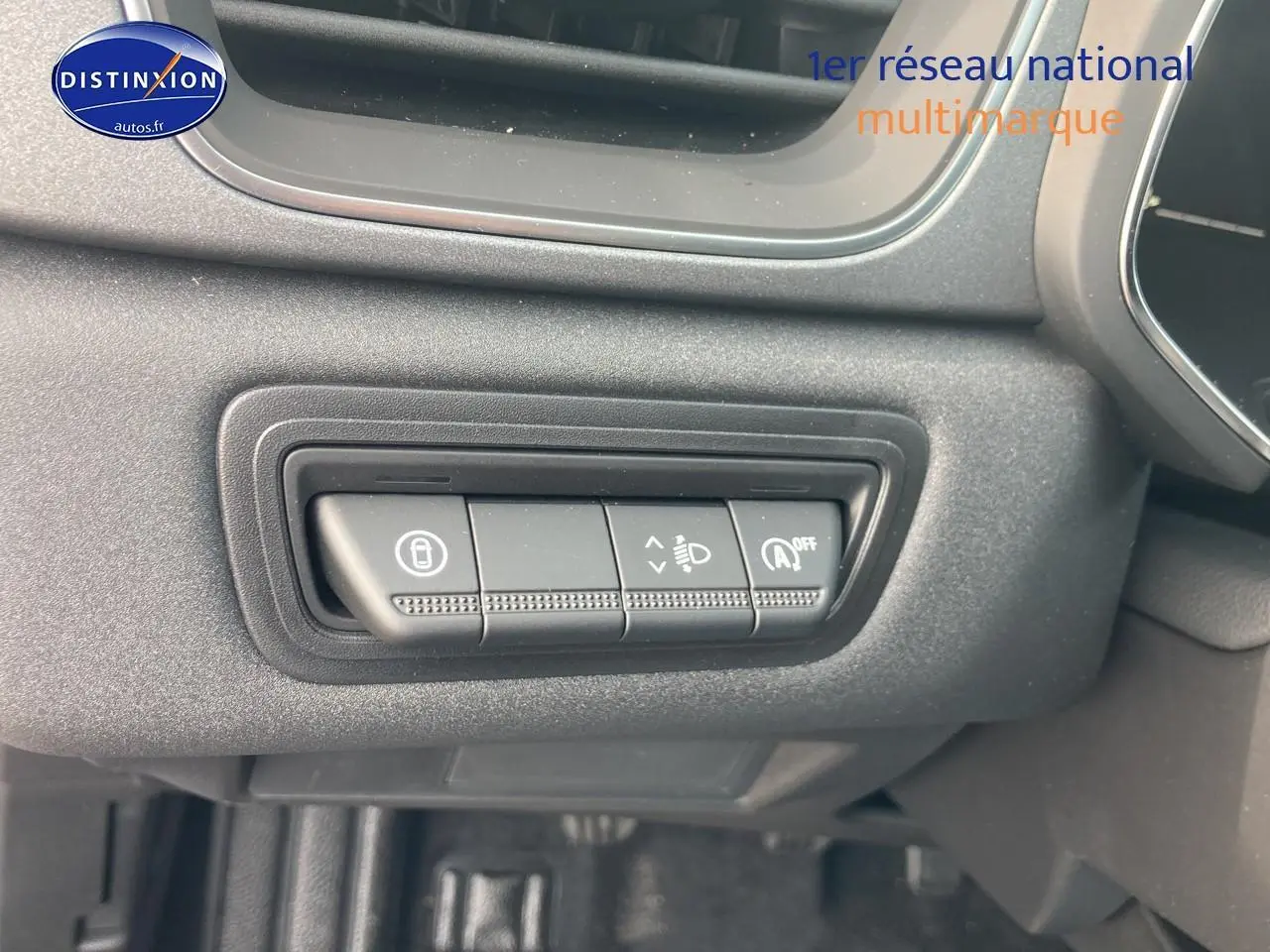 Gros plan sur les commandes de réglage des phares et du système stop-start du tableau de bord du Renault Captur bleu iron.