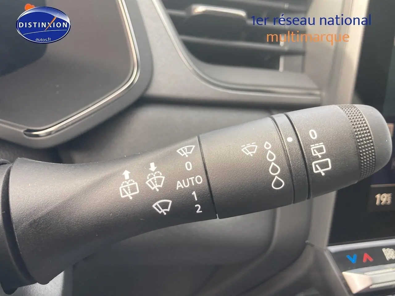 Gros plan sur la commande d’essuie-glace du Renault Captur Bleu Iron, intérieur moderne avec écran tactile partiel visible.