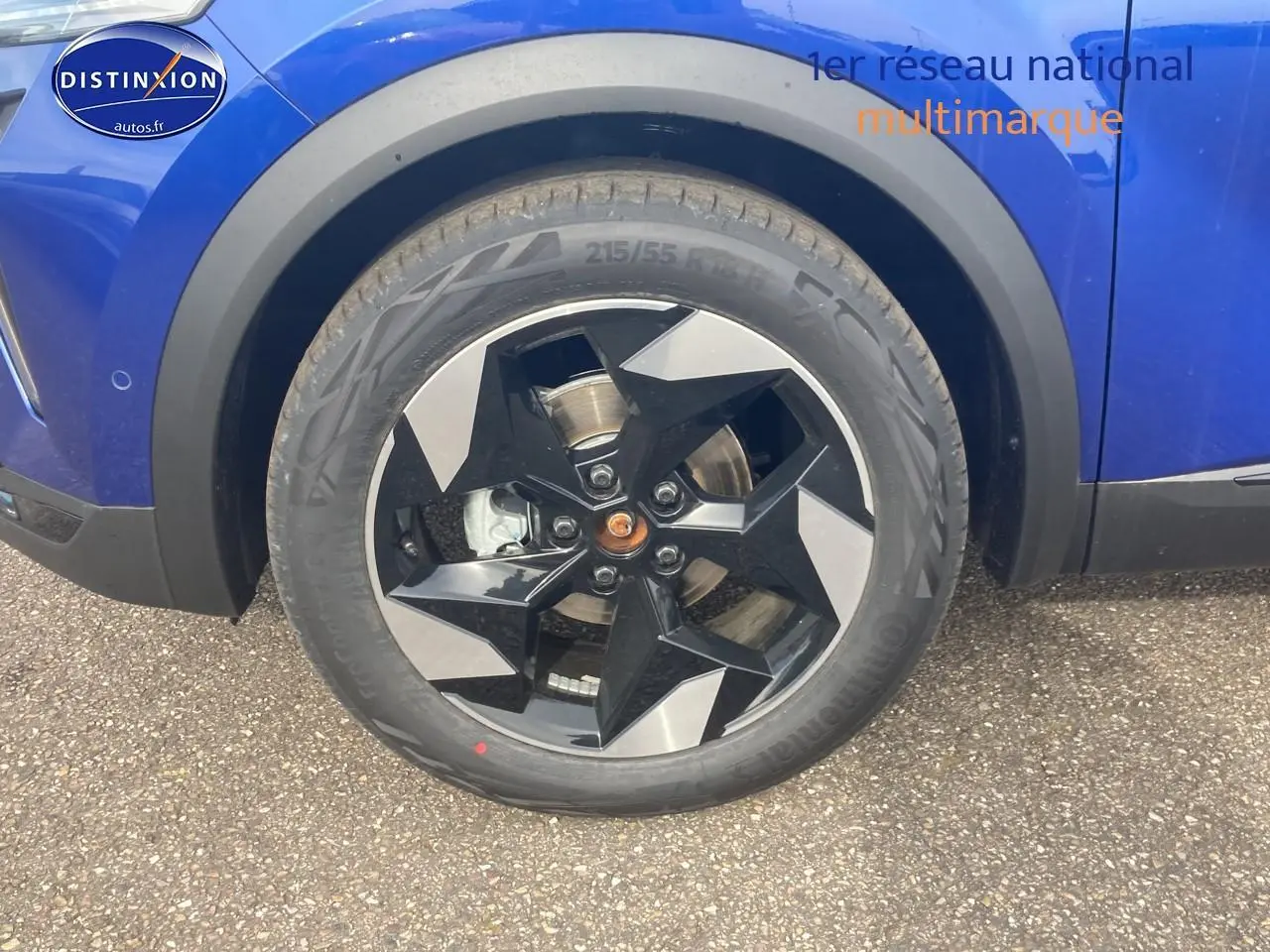 Gros plan sur la roue avant gauche d’un Renault Captur bleu iron avec jante alliage noire et grise.