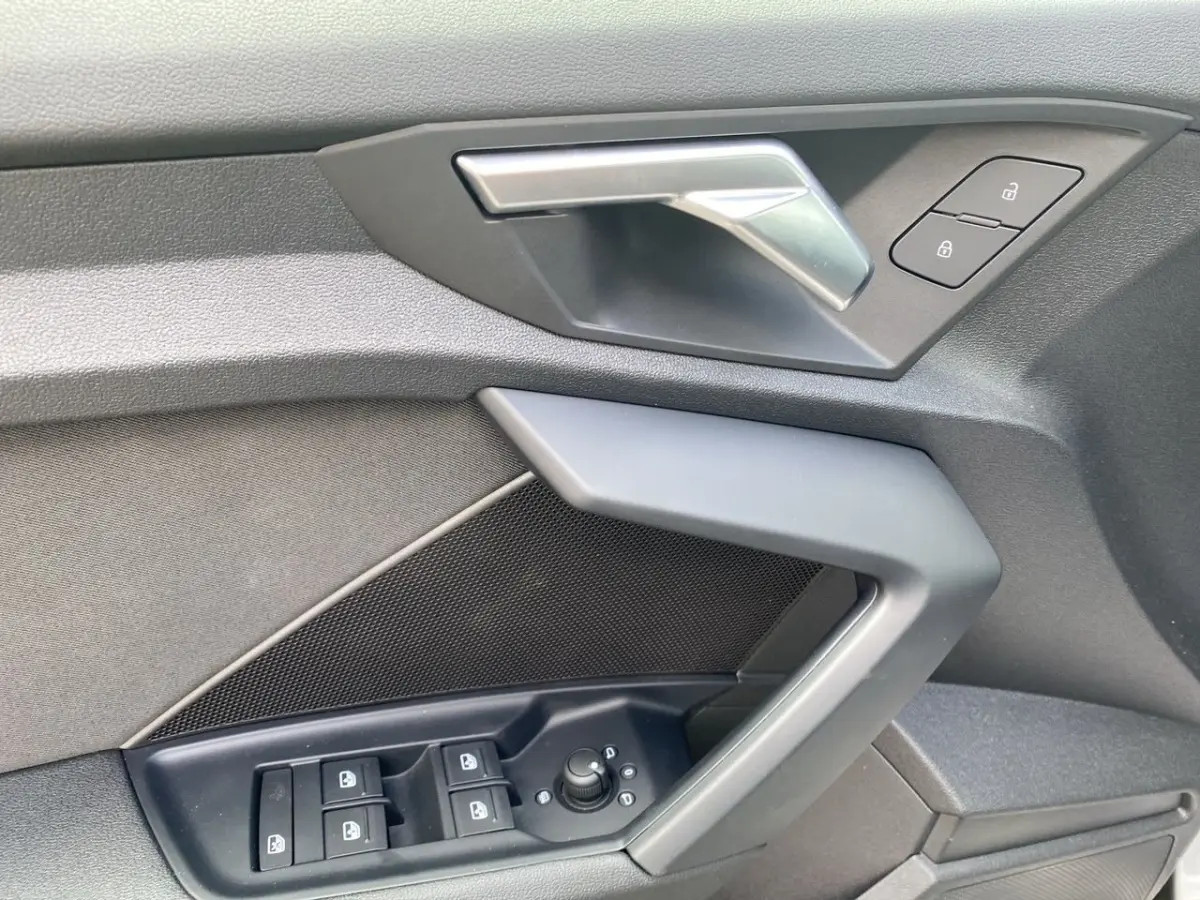 Détail de la porte côté conducteur de l'Audi A3 30 TFSI S Line 2021 gris foncé, avec commandes électriques et poignée argentée.