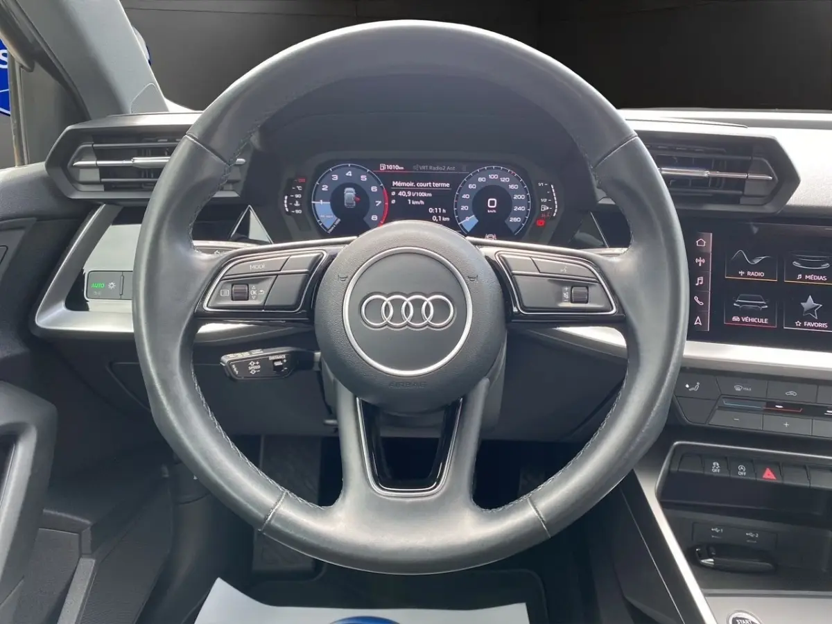 Vue centrée sur le volant cuir noir de l'Audi A3 30 TFSI 110 S Line 2021 avec tableau de bord digital et écran tactile.