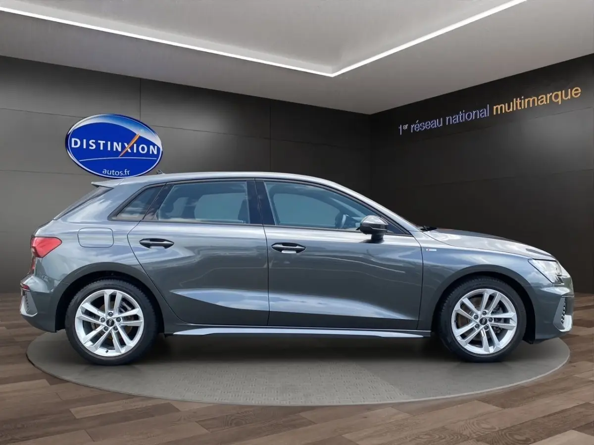 Audi A3 30 TFSI S Line gris foncé vue de profil côté gauche en intérieur showroom avec jantes alliage.