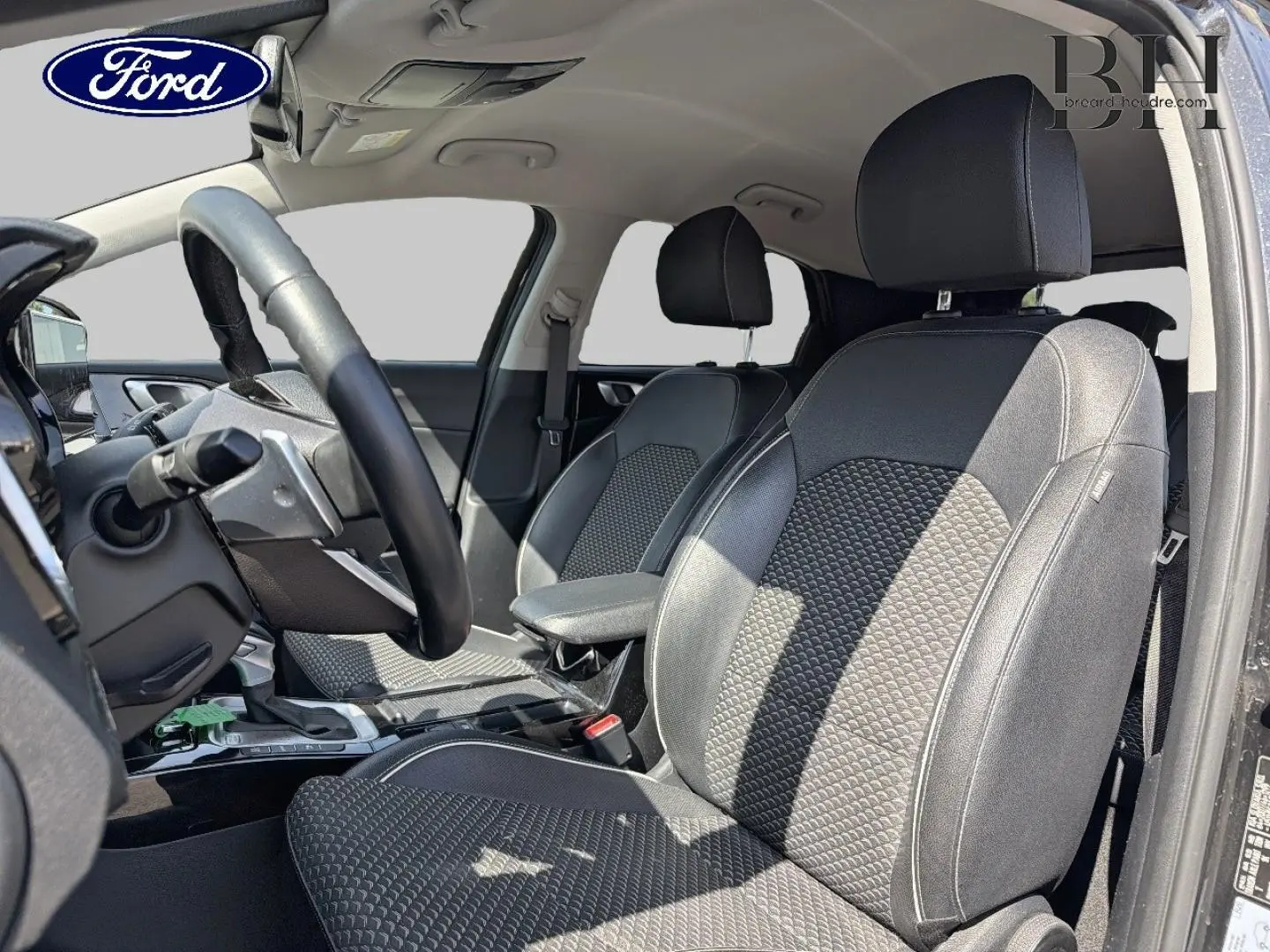 Intérieur avant du KIA Xceed 2022, vue côté conducteur, sièges en tissu noir avec motifs texturés et volant cuir.
