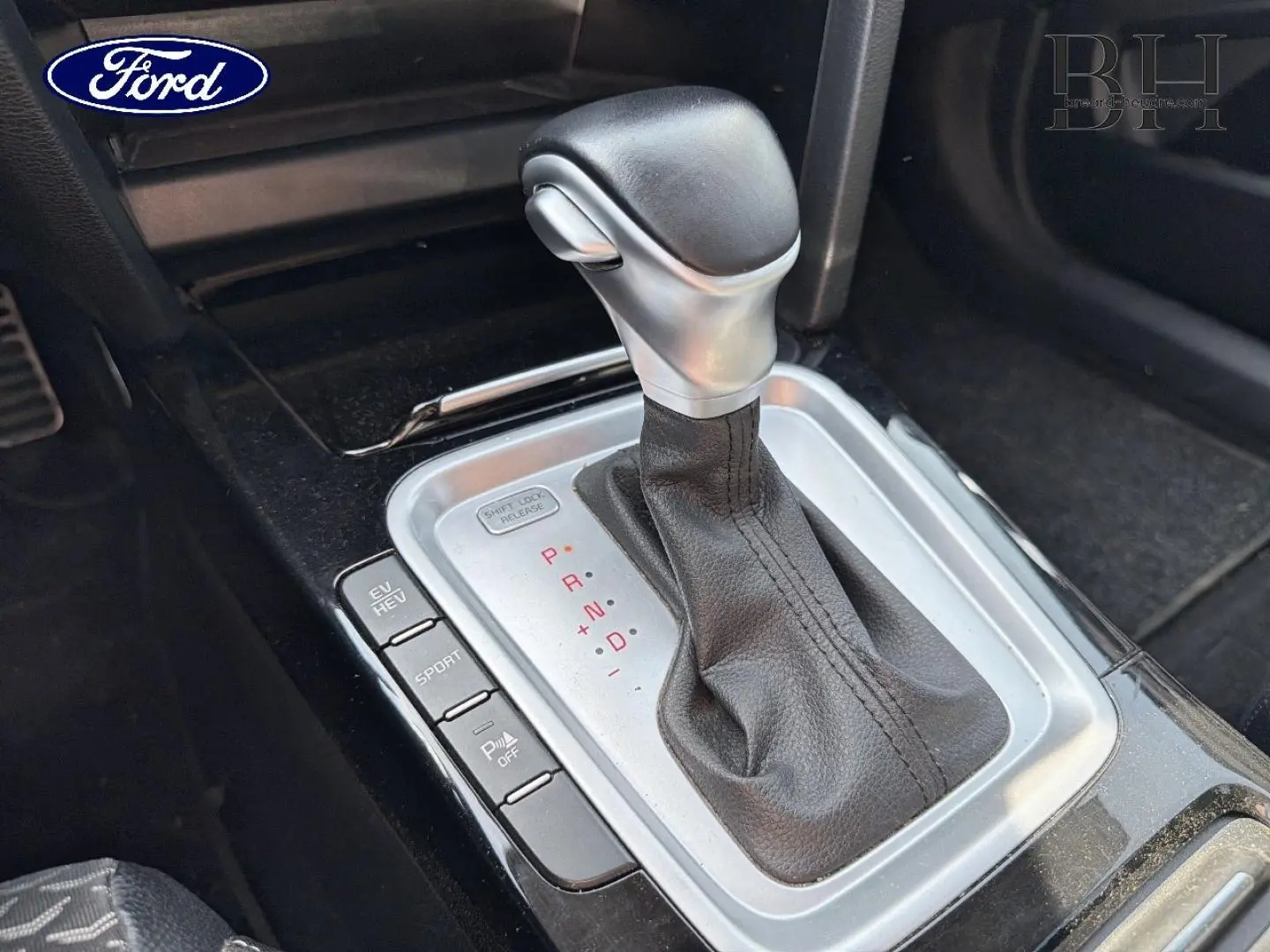 Levier de vitesse automatique en cuir noir avec console argentée, vue rapprochée de l'intérieur d'une KIA Xceed noire.