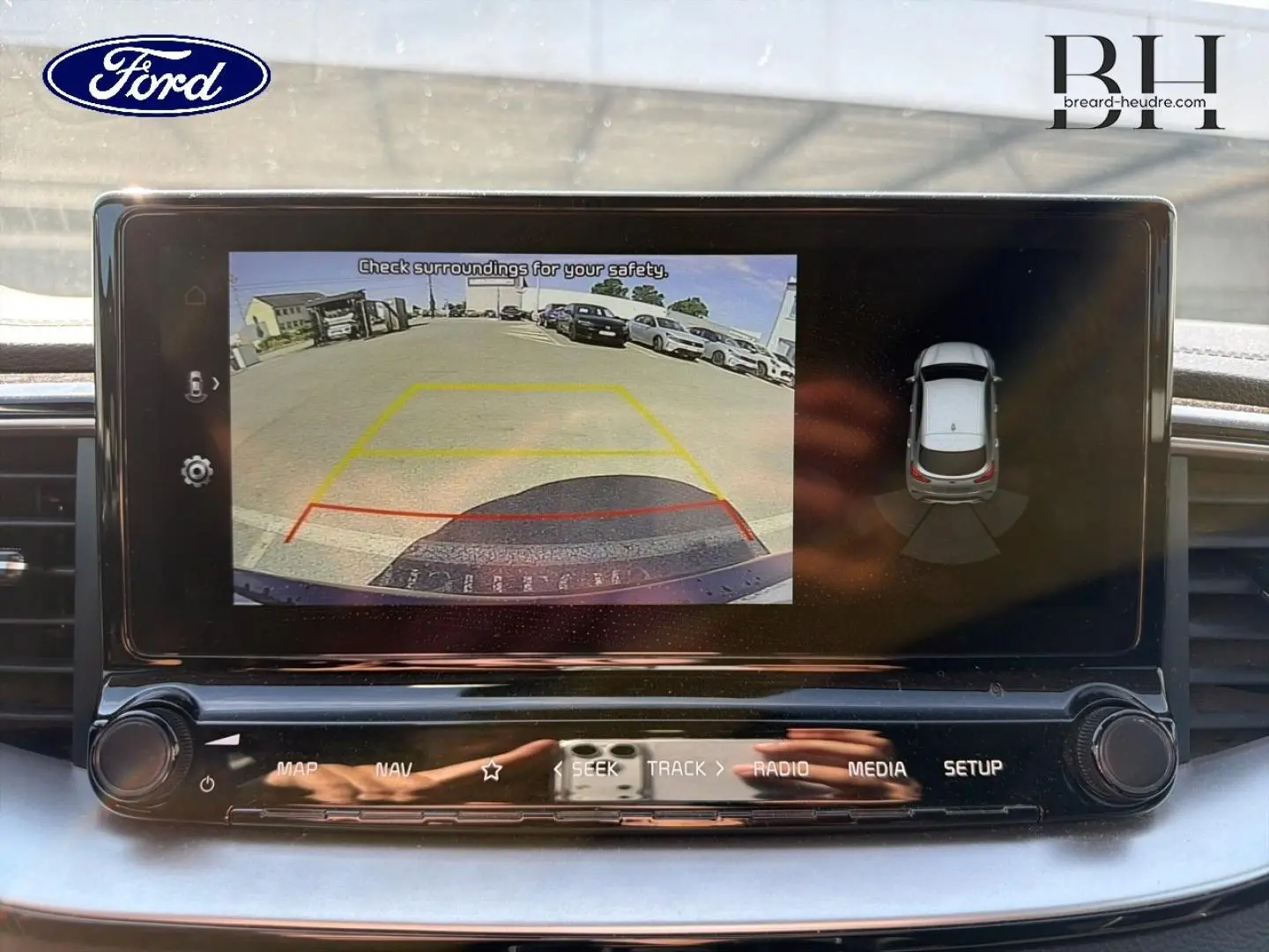 Écran tactile intérieur montrant la caméra de recul et l'affichage 360° d'un véhicule en stationnement.