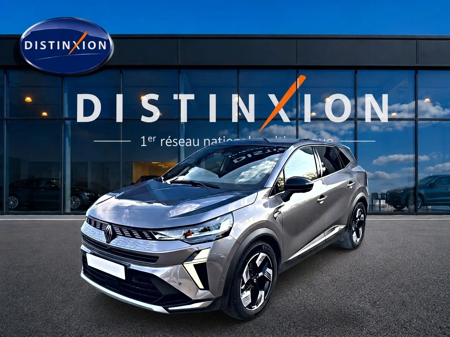 Renault Symbioz gris 3/4 avant droit, SUV hybride avec calandre moderne et jantes bicolores distinctives.