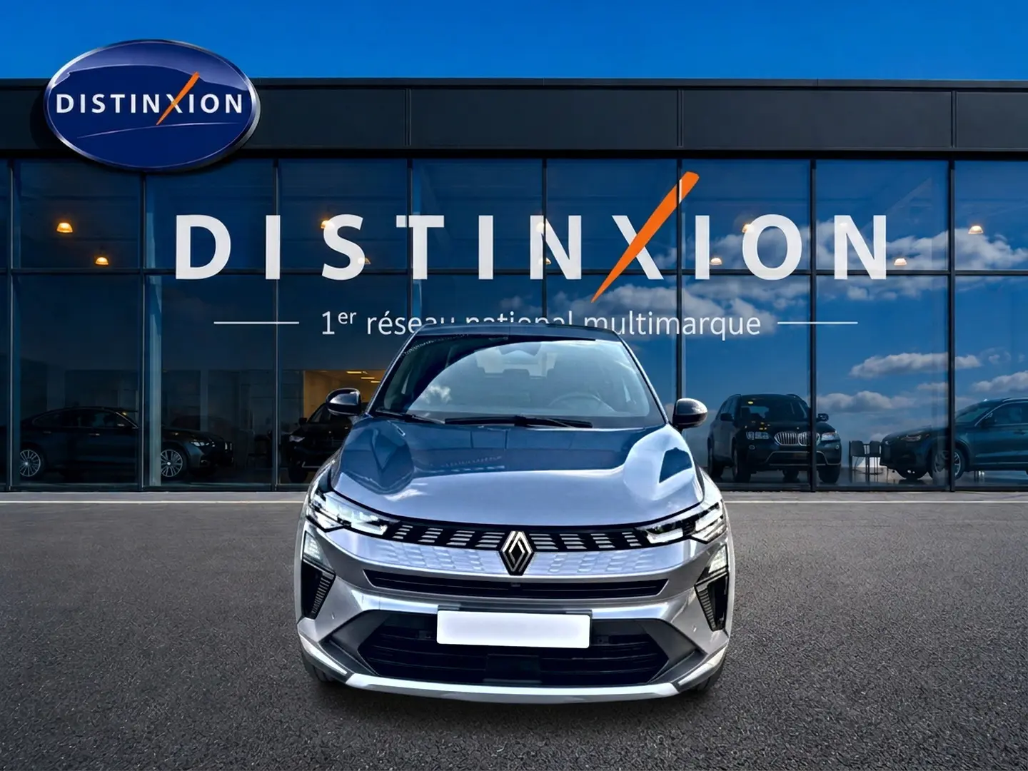Vue frontale d'une Renault Symbioz gris métallisé 2025 devant une vitrine avec logo Distinxion.