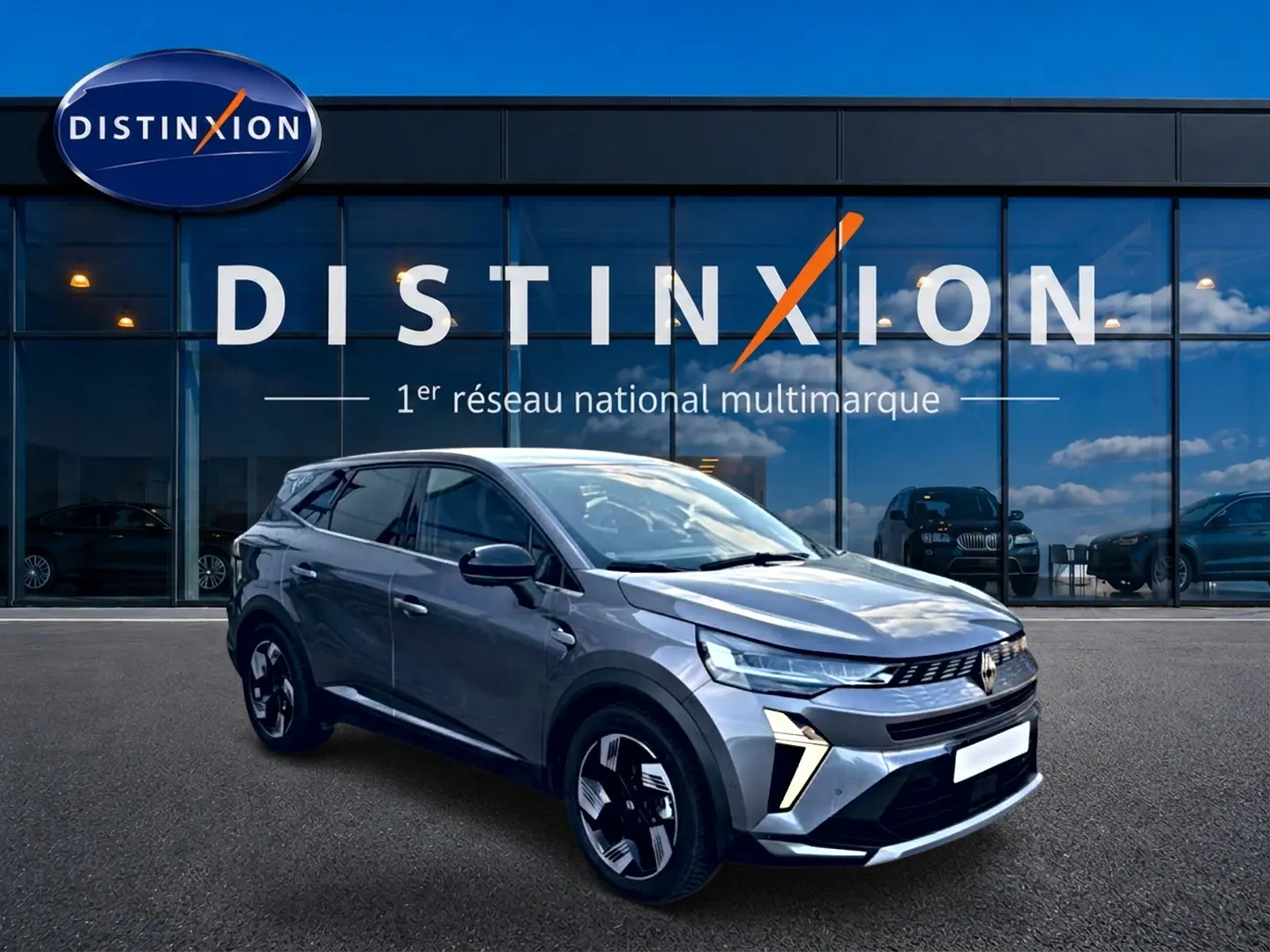 Renault Symbioz gris 3/4 avant droit, SUV hybride avec signature lumineuse distinctive et jantes modernes.