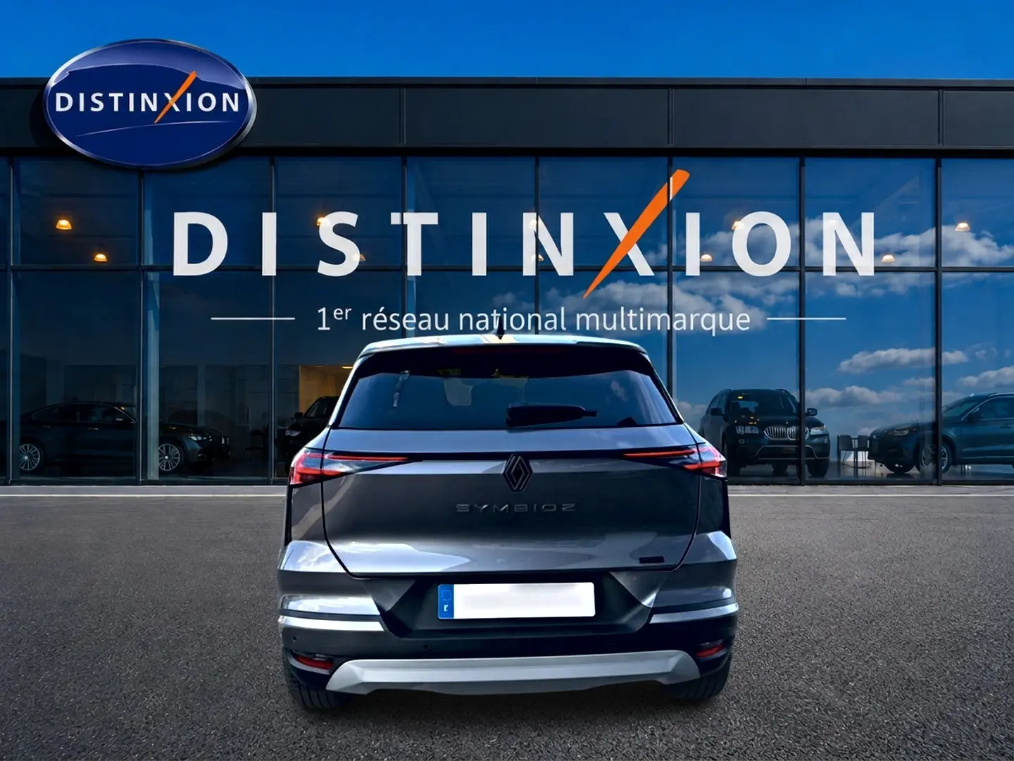 Vue arrière d'un Renault Symbioz gris 2025 stationné devant une vitrine avec logo Distinxion.