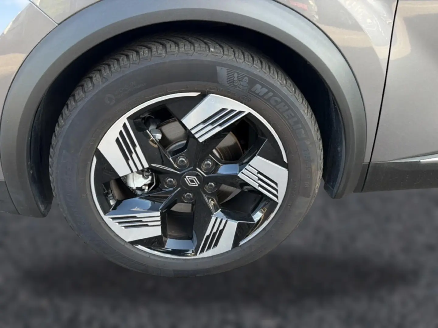 Gros plan sur la roue avant droite du Renault Symbioz gris 2025, avec jante noire et argent au design géométrique.