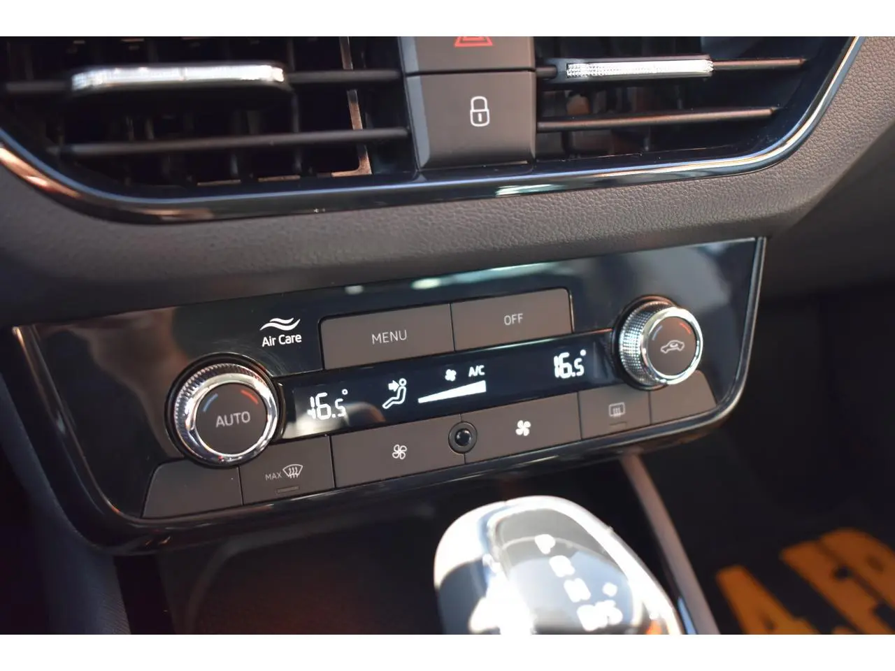 Gros plan sur la console centrale de la Skoda Scala blanche, affichant la climatisation digitale à 16,5°C et la boîte auto.