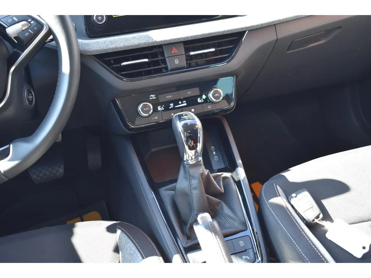 Vue intérieure centrée sur la console centrale et levier de vitesse automatique d'une Skoda Scala blanche glacier, sellerie noire.