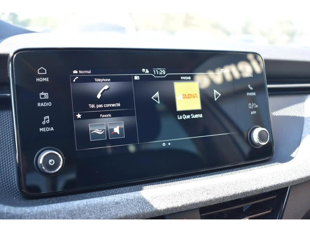 Écran tactile central de la Skoda Scala blanc glacier, affichant les options téléphone et radio FM/DAB.