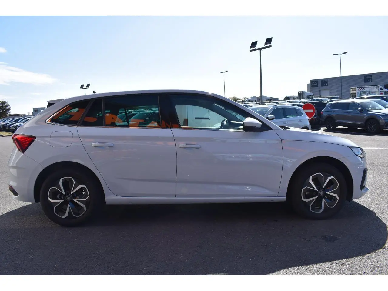 Vue de profil côté gauche d'une Skoda Scala blanc glacier garée en extérieur, avec jantes au design moderne.