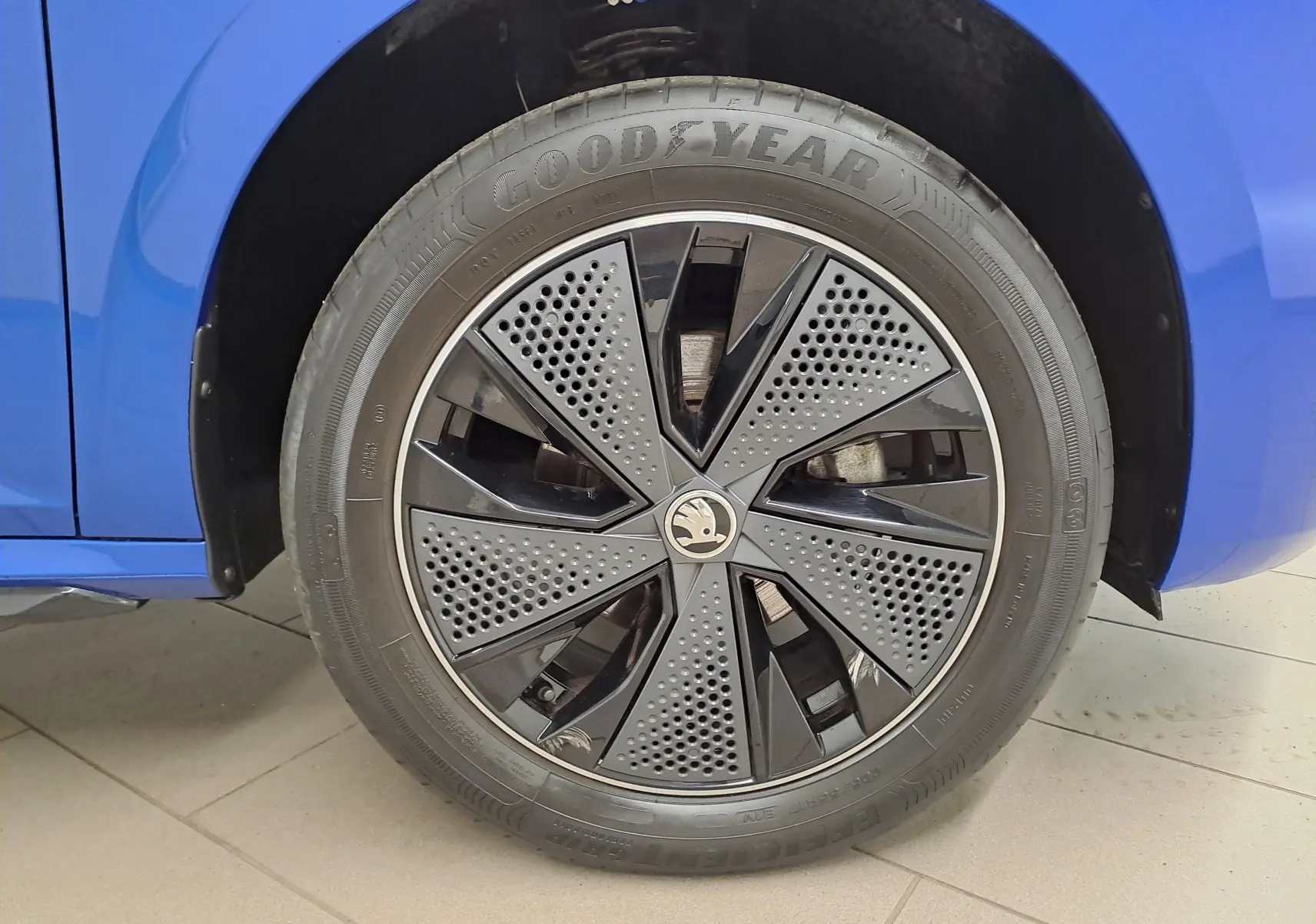Gros plan sur la roue avant gauche du Skoda Kamiq Bleu RS 2024 avec jante noire au design perforé et pneu Goodyear.