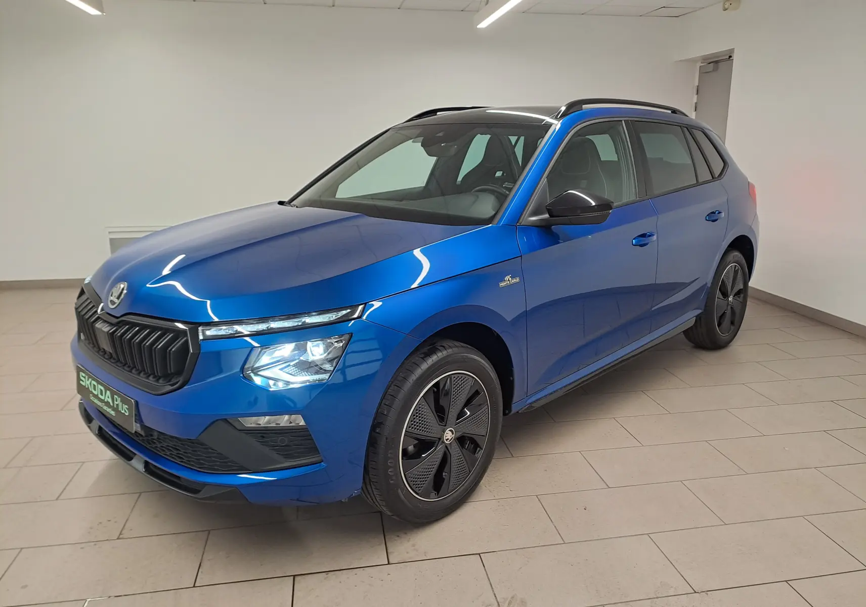 Vue 3/4 avant droite d'un Skoda Kamiq 1.5 TSI 150 DSG7 Monte Carlo bleu RS avec jantes noires et toit noir.