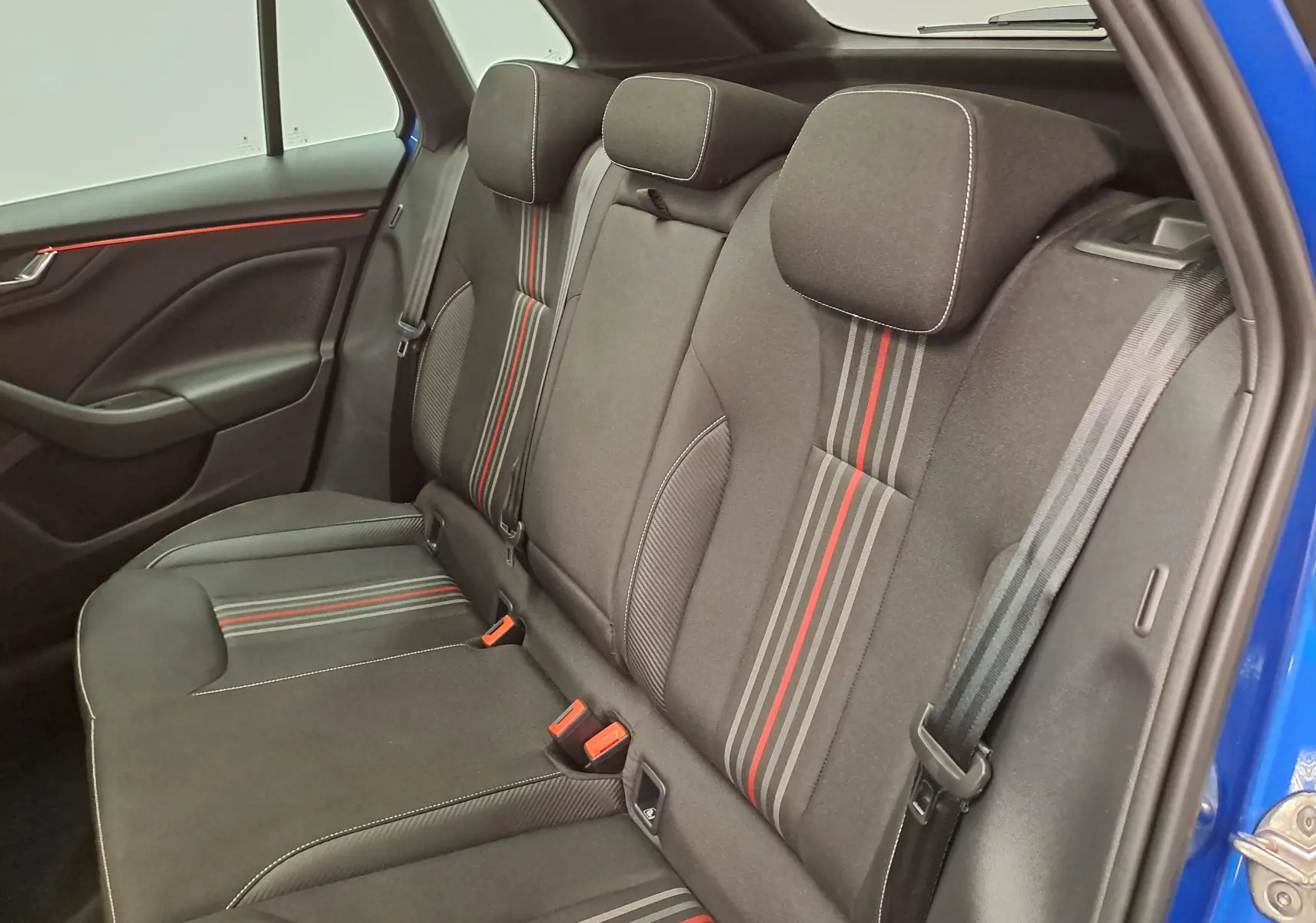 Vue intérieure arrière droite des sièges arrière noirs avec surpiqûres blanches et bandes rouges du Skoda Kamiq Bleu RS 2024 Monte Carlo.