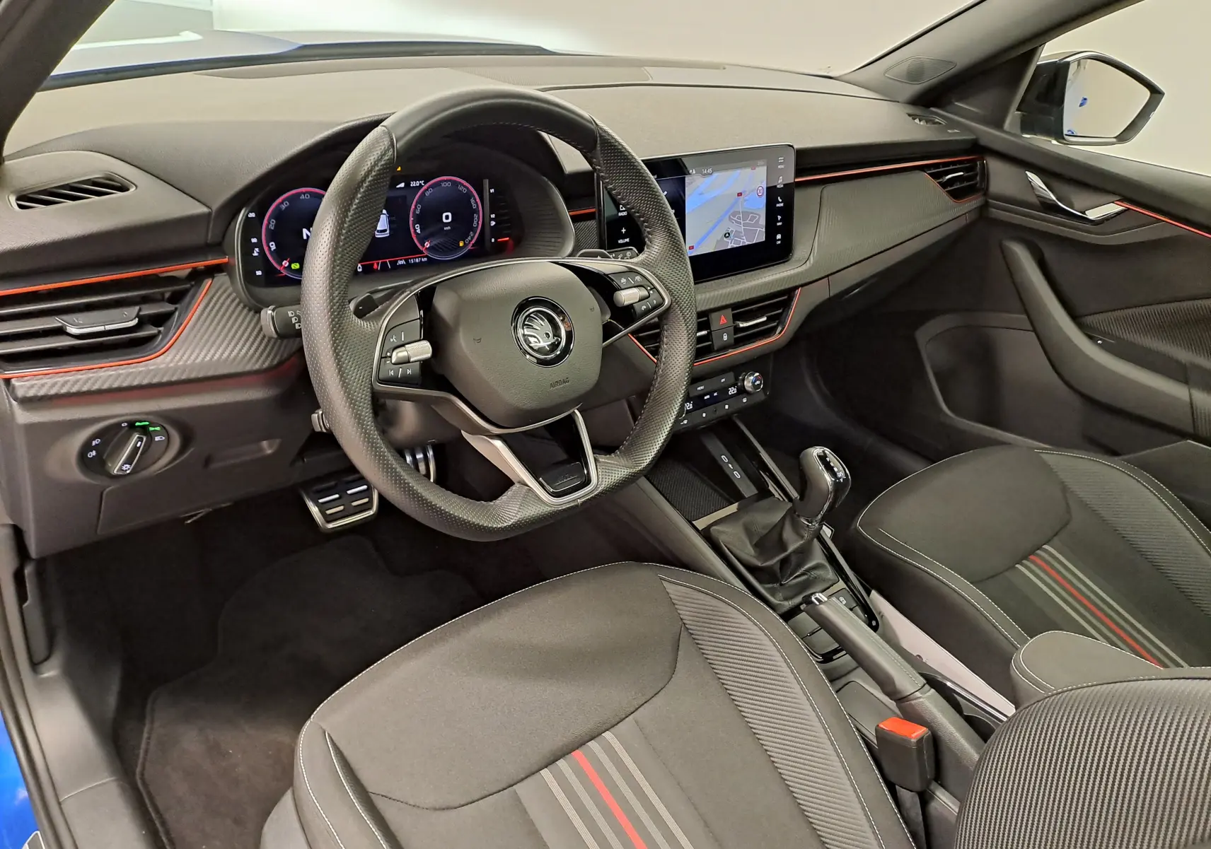 Vue intérieure côté conducteur du Skoda Kamiq 2024 bleu RS, avec tableau de bord digital et finitions sport rouges.