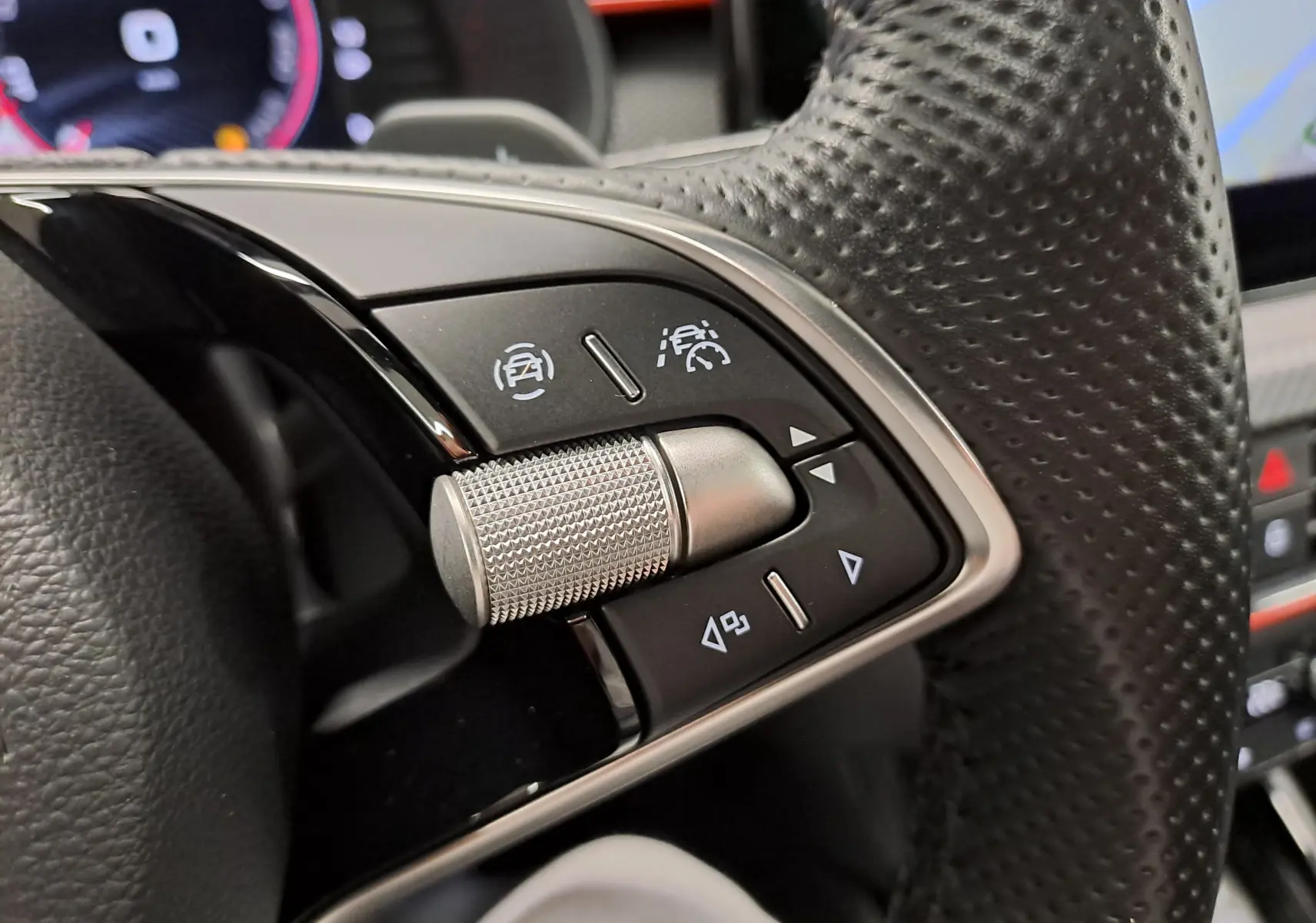 Gros plan sur les commandes au volant à droite du Skoda Kamiq 2024, avec molette métallique et boutons noirs.