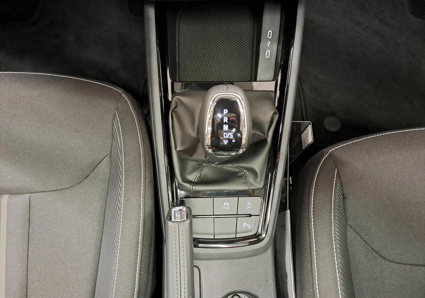 Vue plongeante sur la console centrale du Skoda Kamiq 2024, avec levier de vitesse automatique et sièges gris.