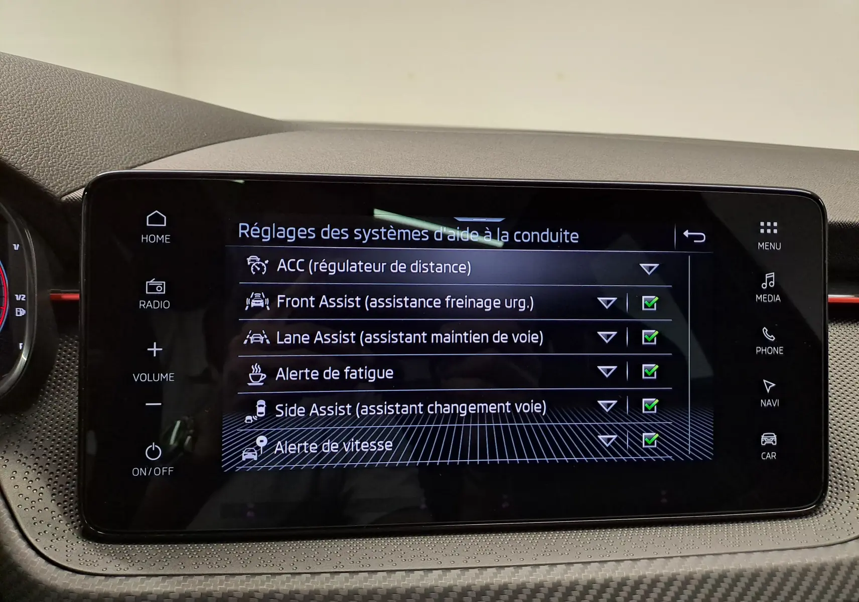 Écran tactile central du Skoda Kamiq 2024 affichant les réglages des aides à la conduite avec interface noire et boutons tactiles.