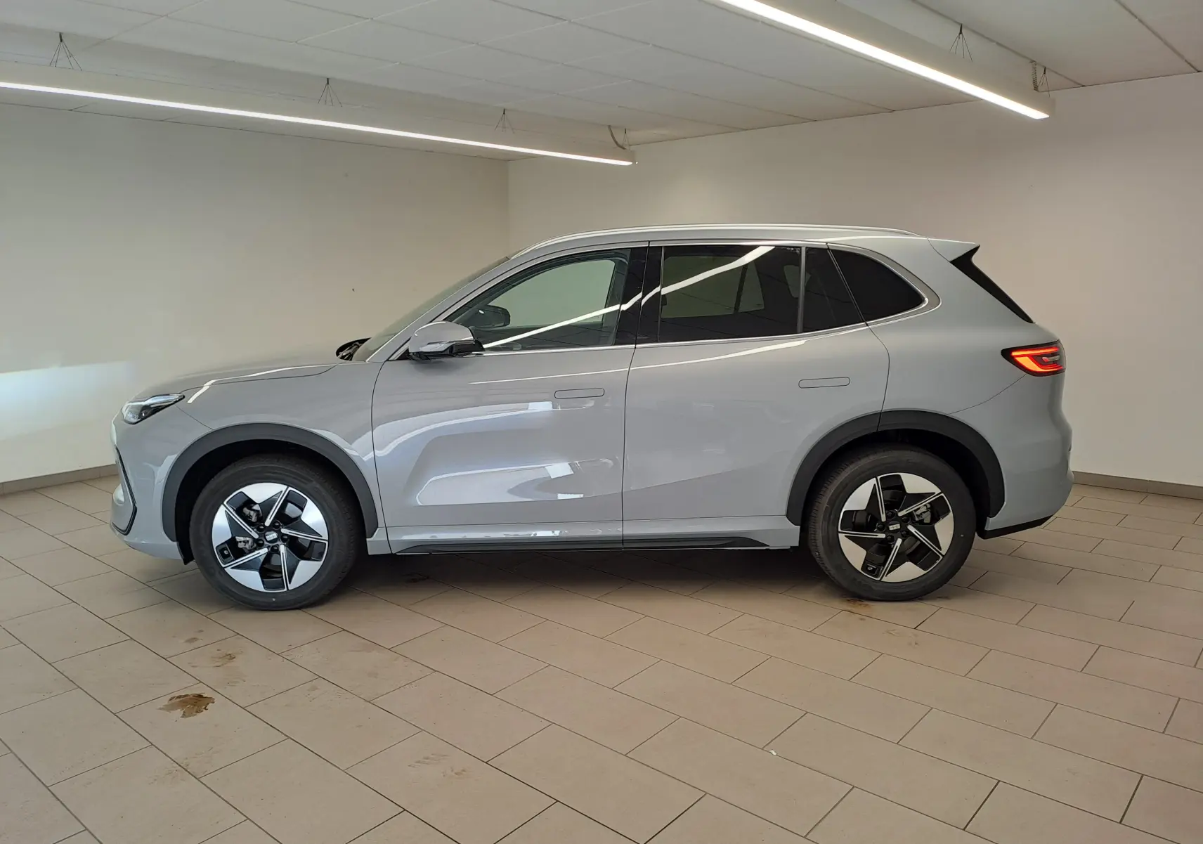 Vue de profil côté gauche du SUV électrique Geely E5 PRO 218ch gris Moonlight avec jantes modernes en intérieur.