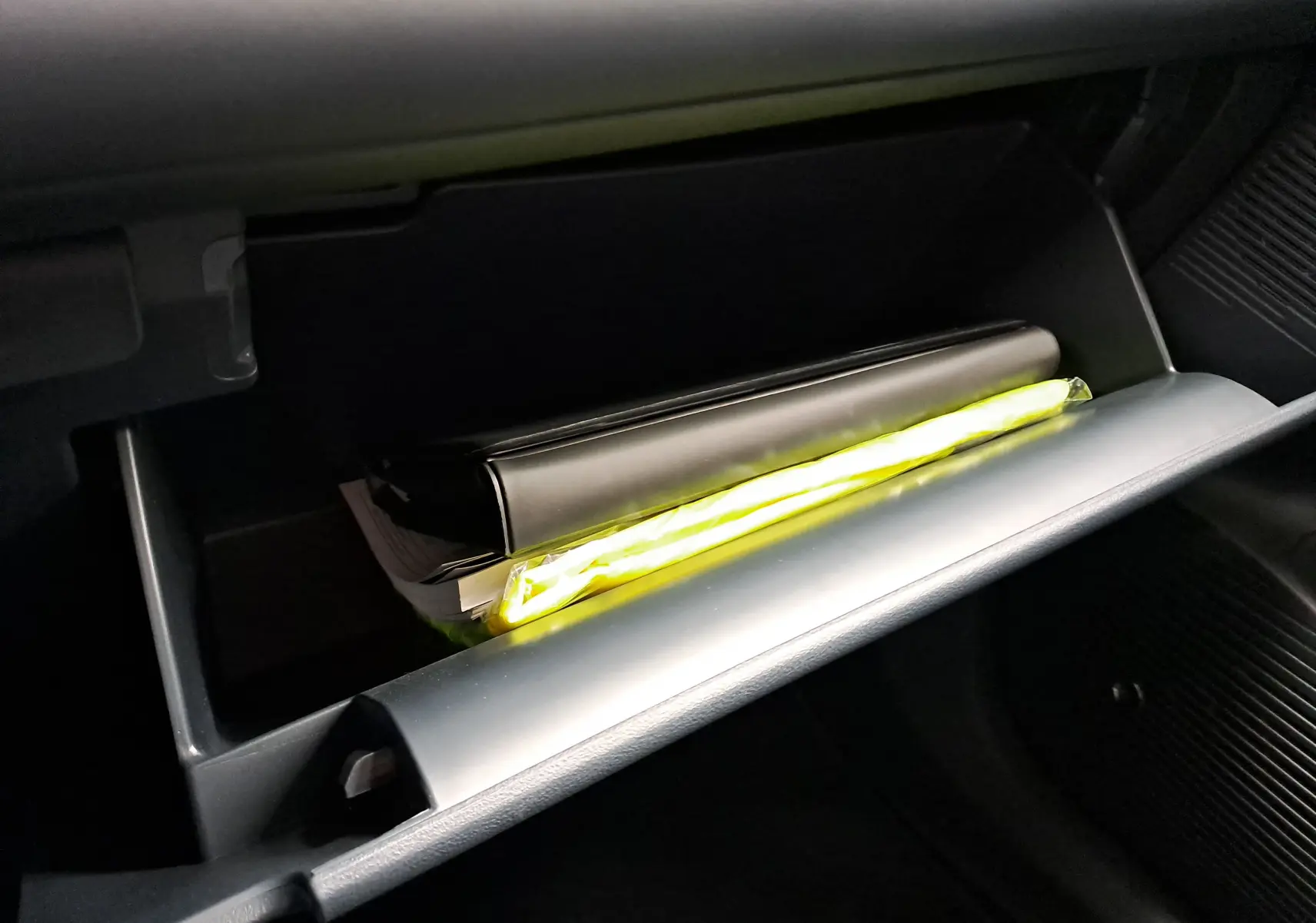 Coffre à gants ouvert du Geely E5 PRO 218ch 60kWh 2026 avec manuel et gilet jaune visible à l'intérieur.
