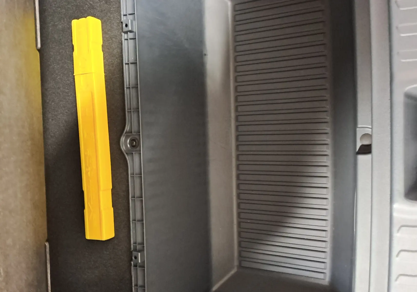 Coffre de rangement intérieur noir avec un triangle de signalisation jaune dans un Geely E5 PRO gris Moonlight 2026.