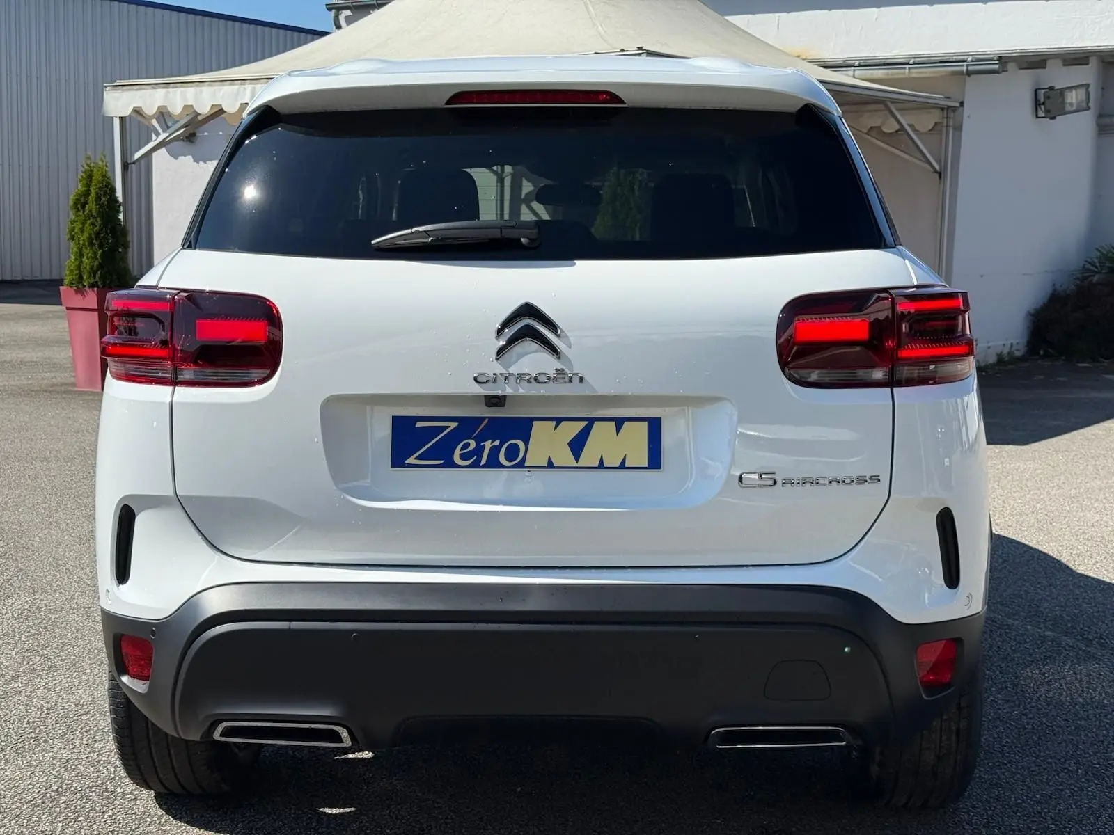 Vue arrière d'un Citroën C5 Aircross blanc banquise avec feux rouges et double sortie d'échappement intégrée.