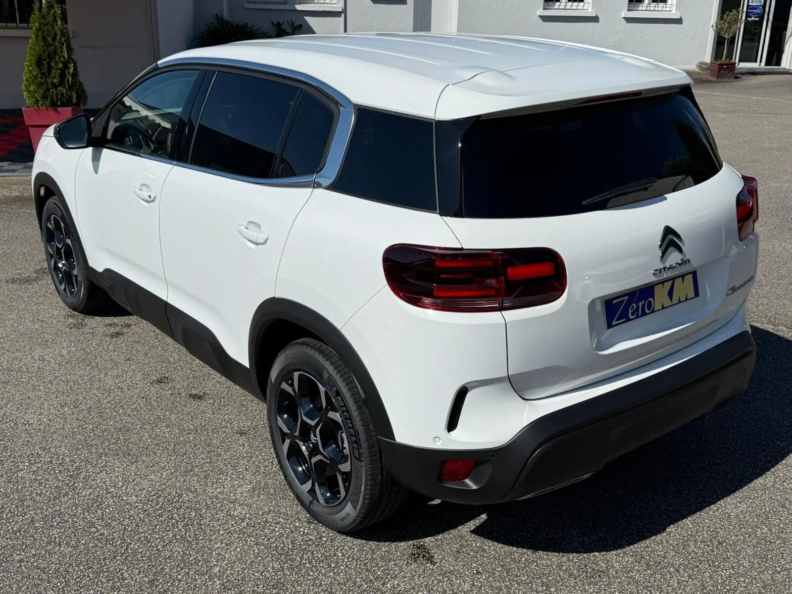 Vue 3/4 arrière droite du Citroën C5 Aircross blanc banquise avec jantes noires et vitres teintées.