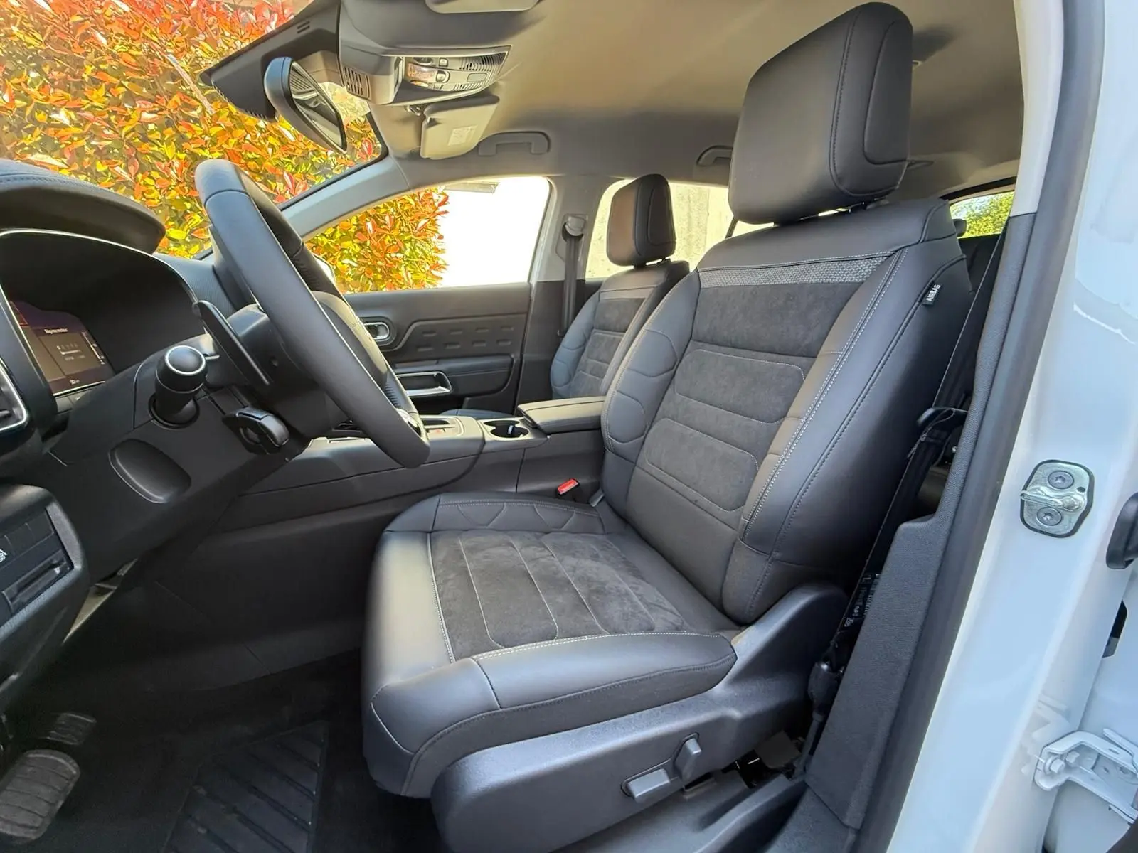 Vue côté conducteur de l'intérieur du Citroën C5 Aircross blanc banquise, sièges cuir et alcantara noirs avec surpiqûres grises.