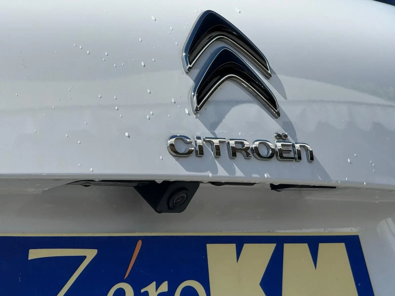 Gros plan sur l'arrière blanc banquise d'une Citroën C5 Aircross 2024, avec logo et caméra de recul visible.