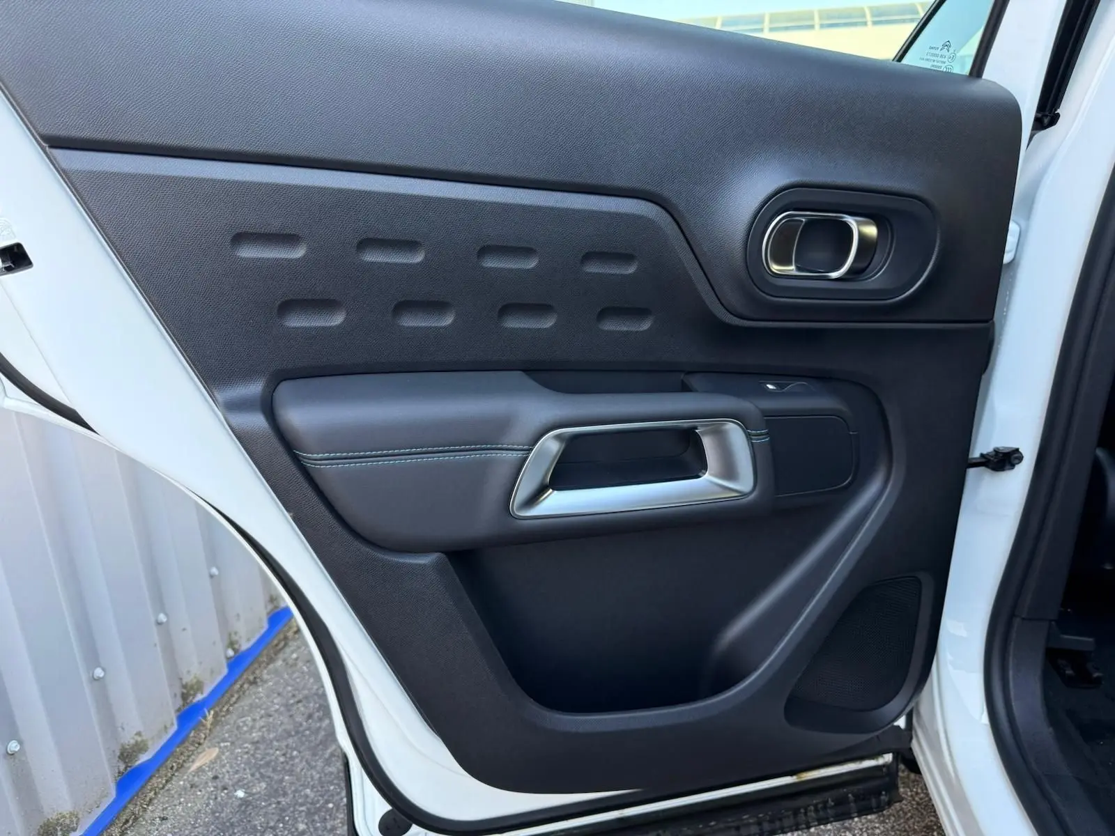 Vue rapprochée de la porte arrière gauche blanche banquise du Citroën C5 Aircross 2024 avec poignée intérieure design.