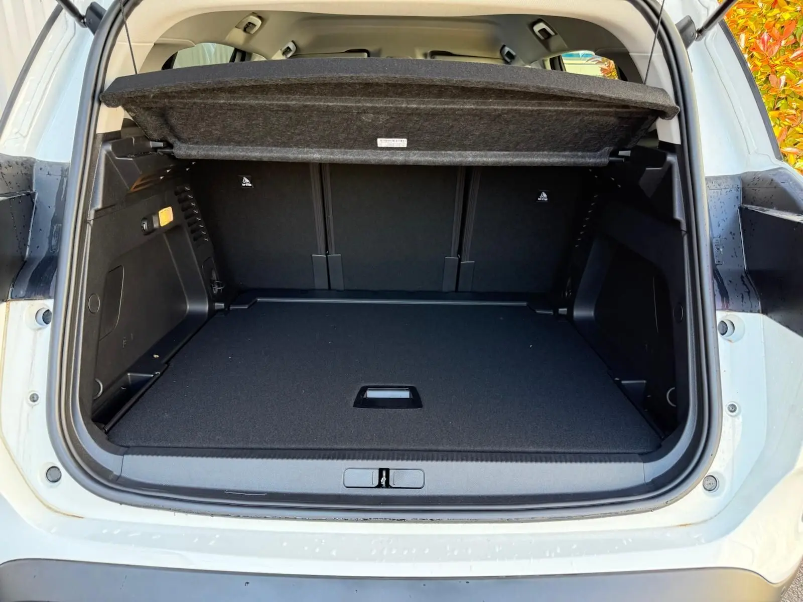 Coffre ouvert vu de l'arrière d'un Citroën C5 Aircross blanc banquise, espace de chargement spacieux et couvert amovible.