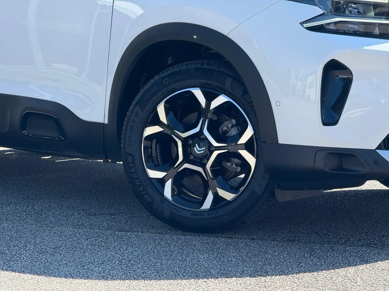 Gros plan sur la roue avant droite blanche banquise du Citroën C5 Aircross 2024 avec jante noire et argentée design urbain.
