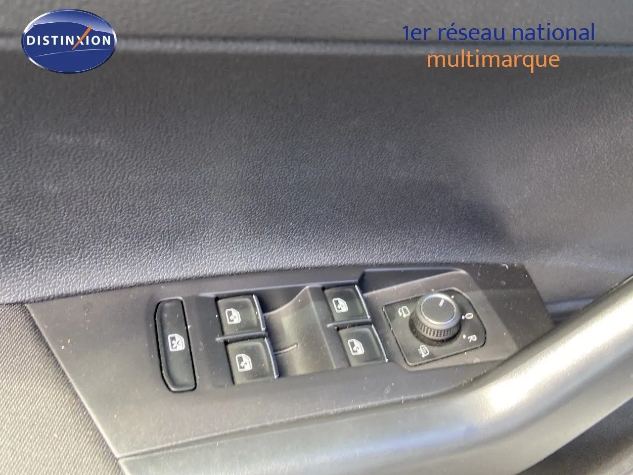 Gros plan sur les commandes de lève-vitres et réglage des rétroviseurs côté conducteur d'une Volkswagen Polo argentée.