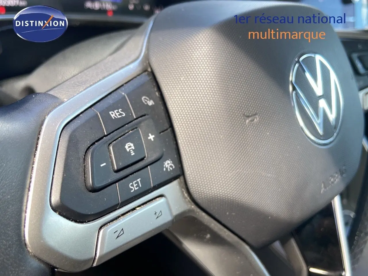 Gros plan sur le volant de la Volkswagen Polo 2023 avec commandes intégrées et logo VW argenté au centre.