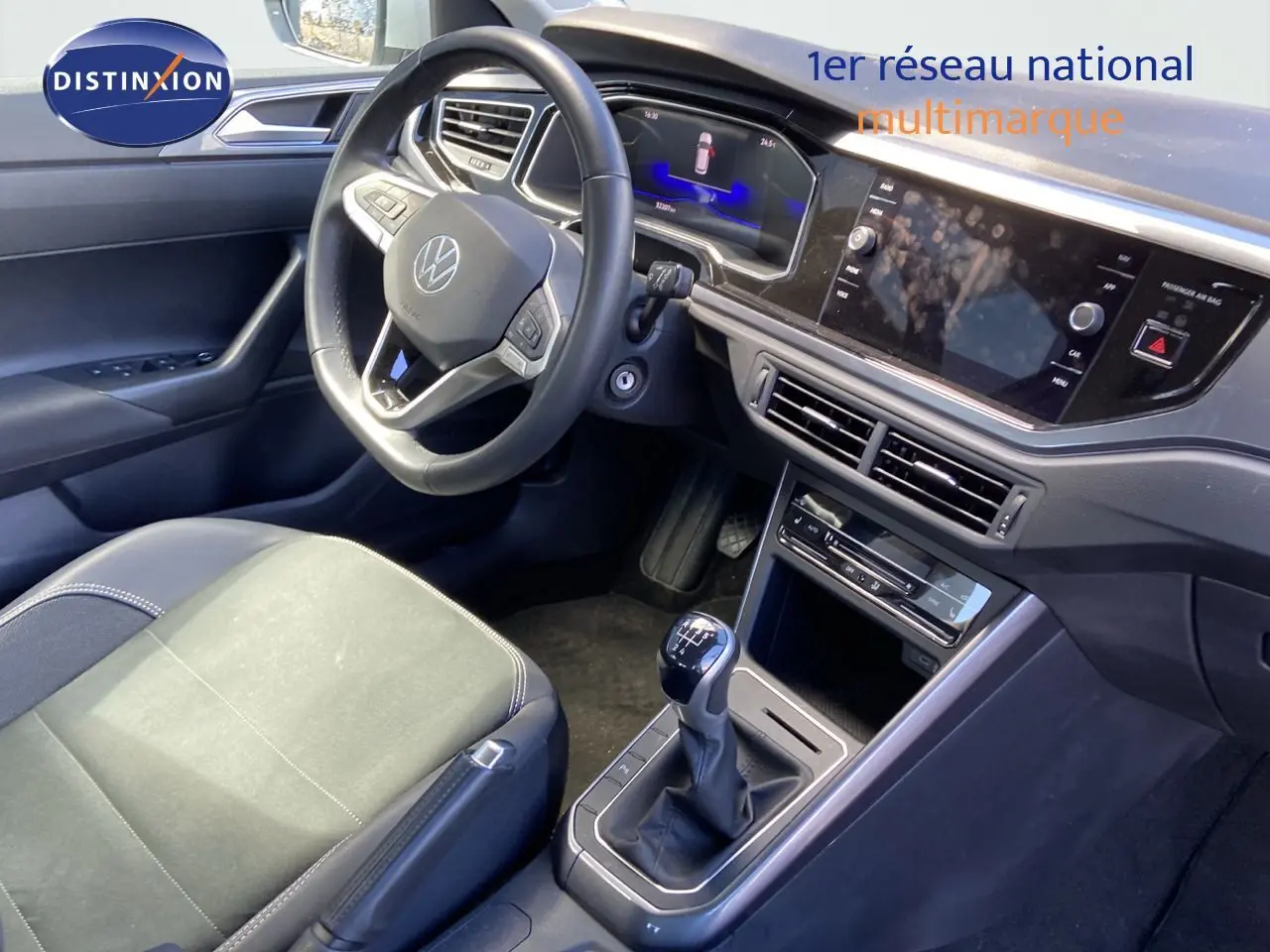 Intérieur avant gauche de Volkswagen Polo 2023 argent, volant multifonctions, boîte manuelle et tableau de bord digital.