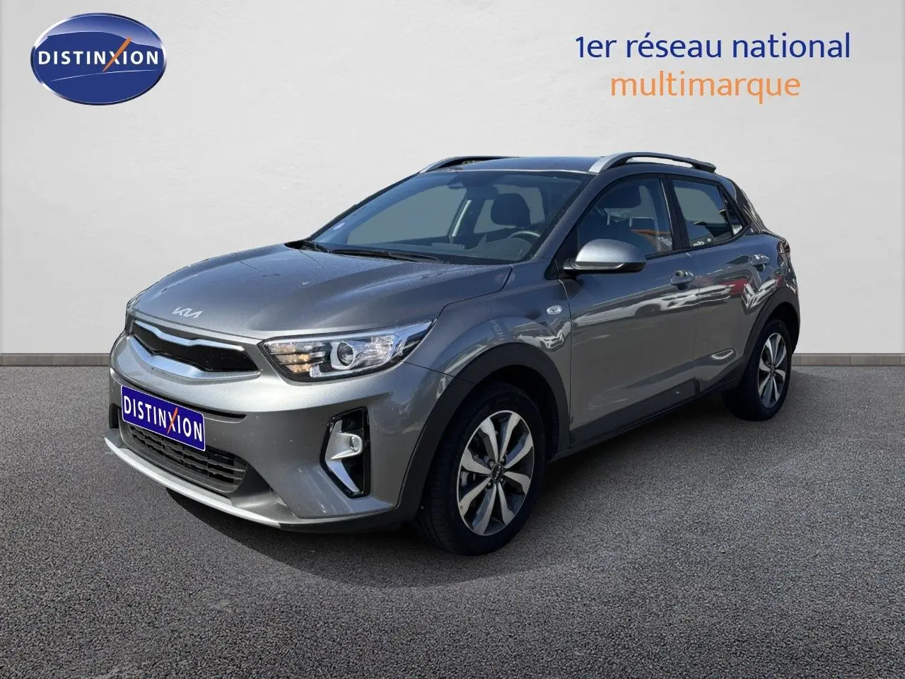 KIA STONIC gris météore en 3/4 avant droit, avec jantes bi-ton et toit ouvrant visible sur fond neutre.