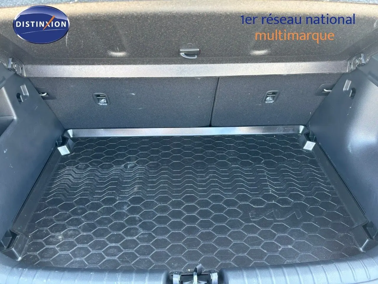 Coffre spacieux du Kia Stonic gris météore 2024, vue intérieure avec tapis de sol en caoutchouc à motif hexagonal.