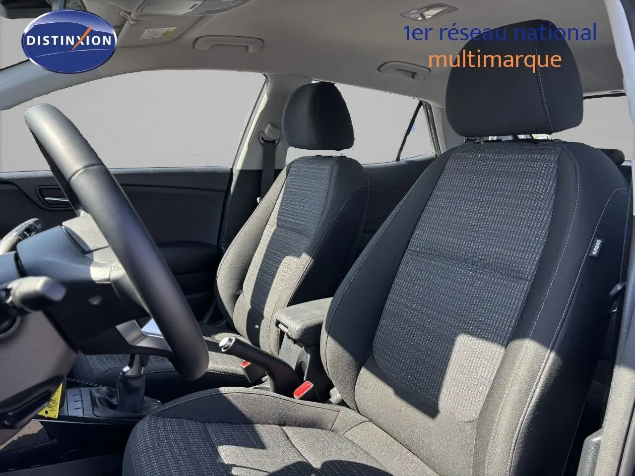 Intérieur du Kia Stonic 2024 montrant les sièges avant en tissu gris et le volant côté gauche.